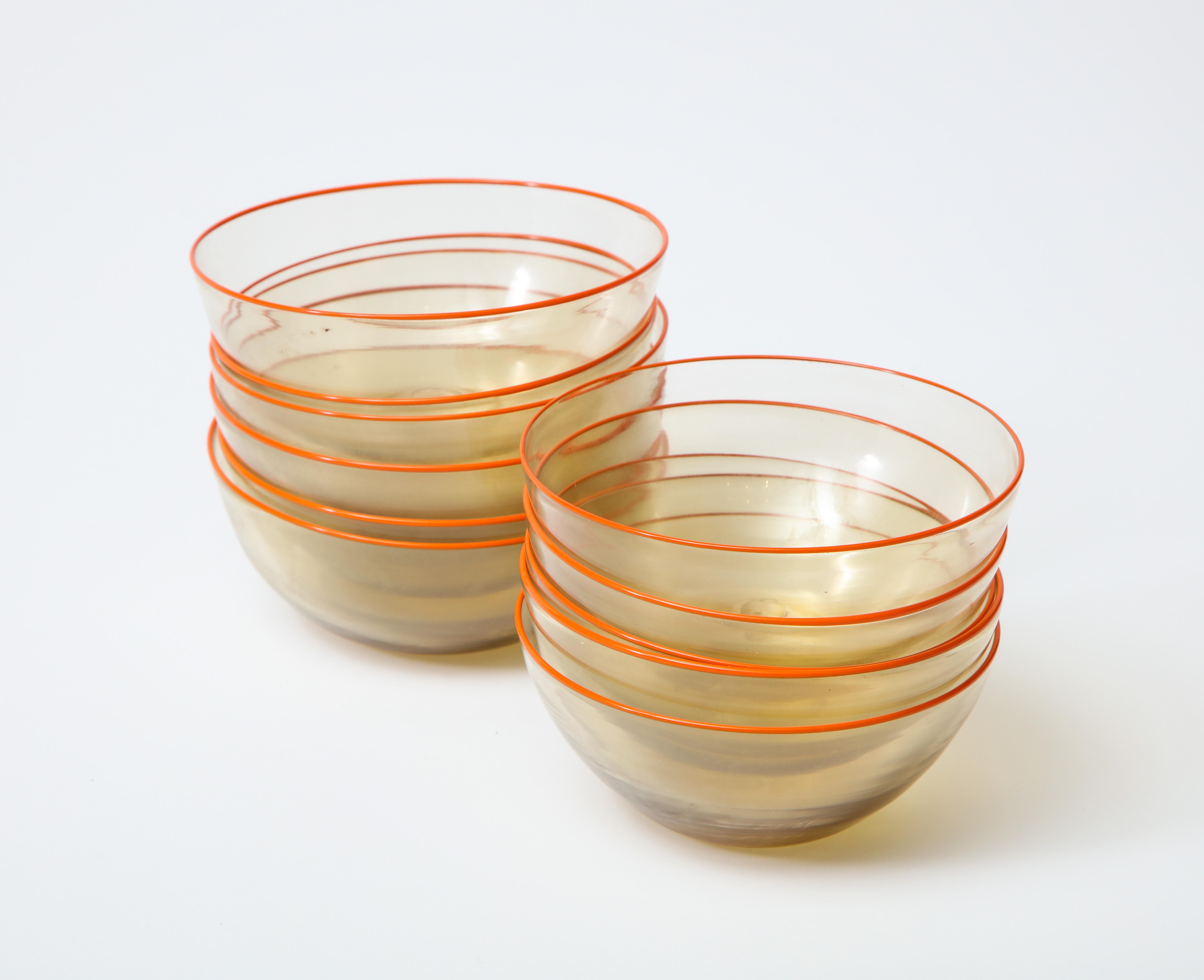A set of 11 clear hand blown Murano glass bowls with orange rims. Delicate, classic midcentury look.