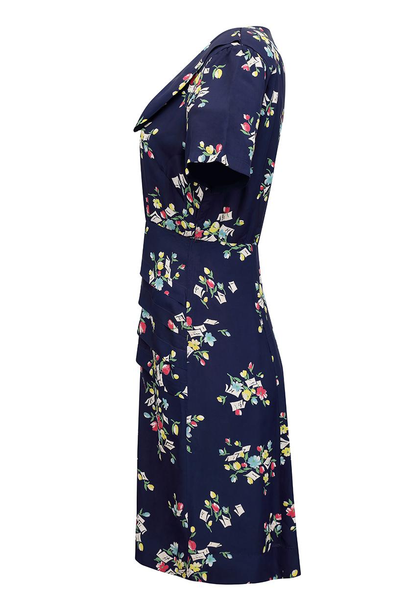 This charming 1940s navy blue novelty print silk dress is a beautiful example of the style and elegance of the era and has some lovely design features. The dress is comprised of navy rayon fabric with a pretty design depicting letters and cards