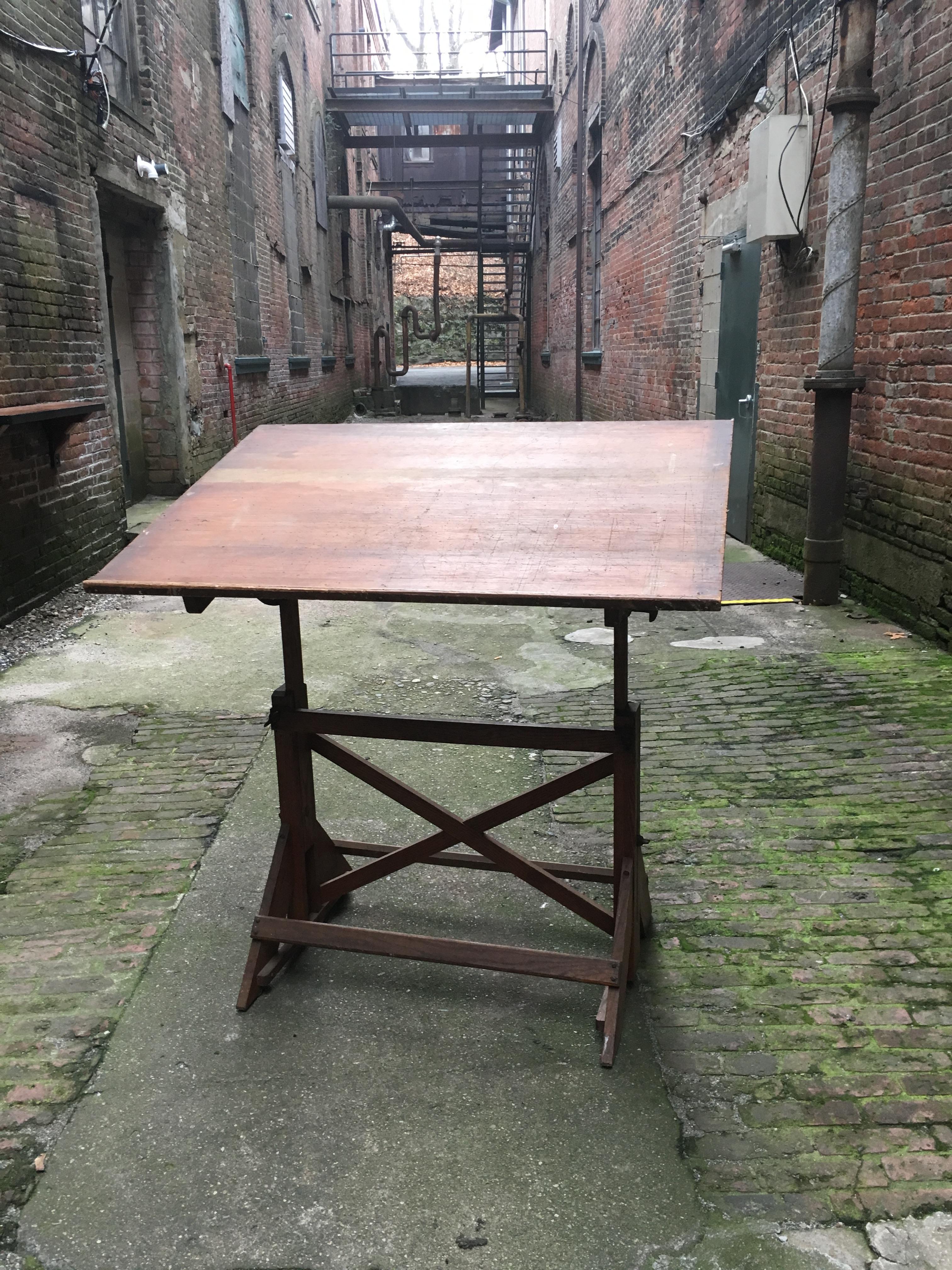 Fully adjustable height and angle. Featuring a solid oak base with pine work surface and iron hardware. The drafting table comes from the estate of marine, landscape and illustrator, Anton Otto Fischer, Woodstock, NY. Wonderful patina and overall