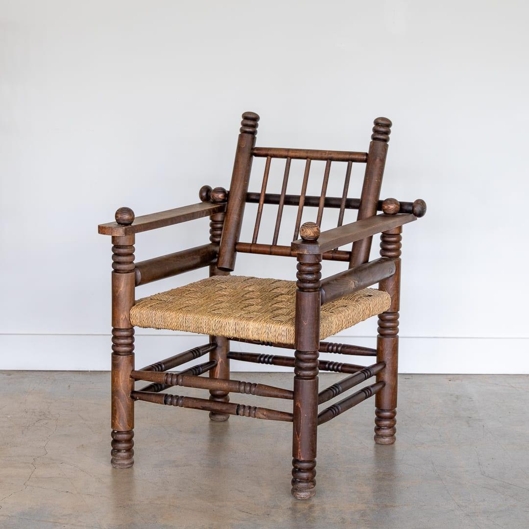 Superbe fauteuil en chêne français et tressé des années 1940 par Charles Dudouyt. Magnifiques détails en bois sculpté sur l'ensemble de l'assise en corde de papier tissée. Le dossier à barreaux réglable se replie vers l'avant sur le siège. La