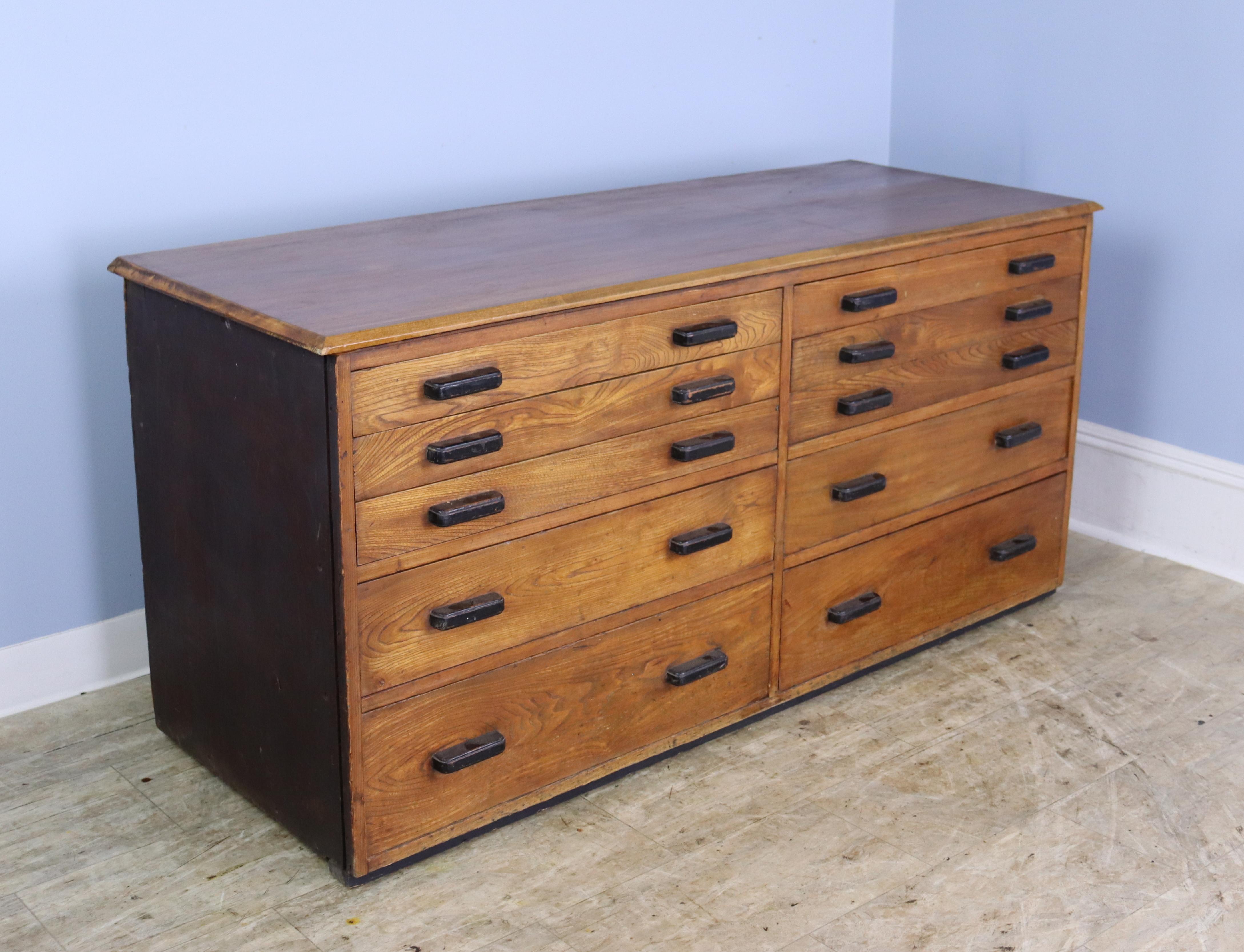 An industrial oak chest or cabinet from 1940's England.  We believe the grooves on the front and back interior of each drawer, shown in thumbnails, may speak to the piece's past as a typesetting cabinet, map or printer's cabinet, blueprint cabinet