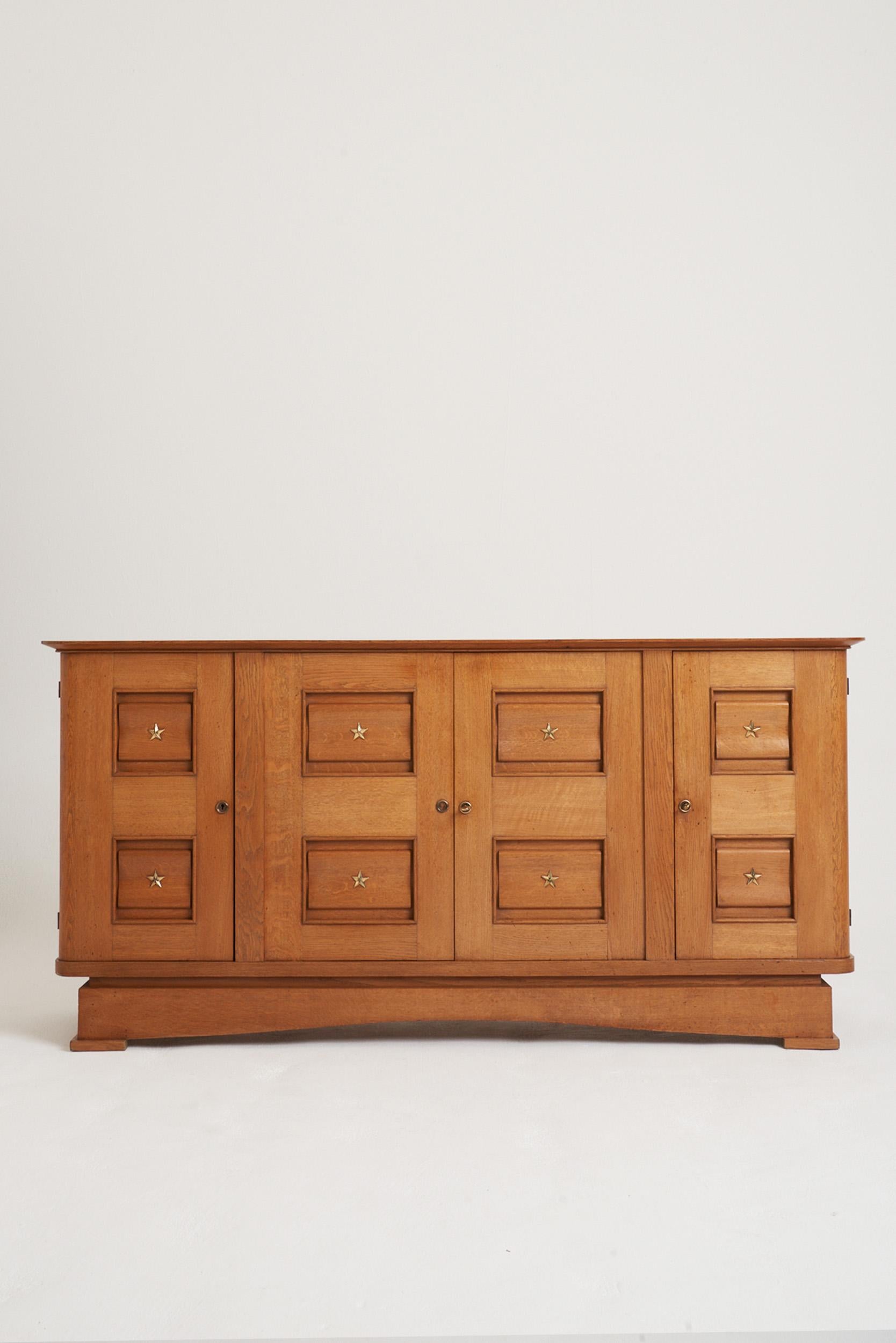 A high quality four-door oak sideboard, with bronze stars adornments.
France, circa 1940.