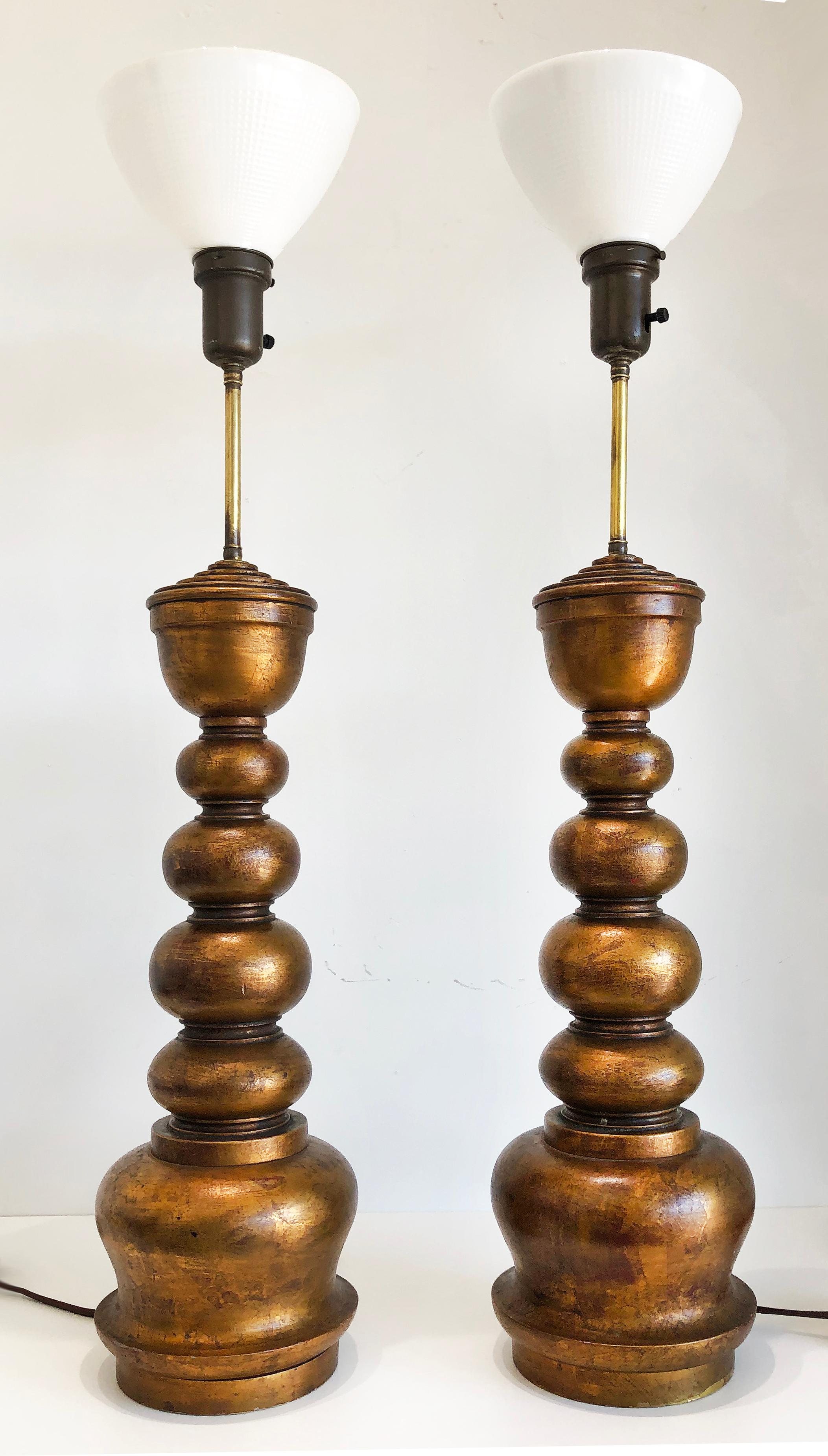 1940s overscaled giltwood lamps attributed to James Mont, Pair

Offered for sale is a pair of overscaled 1940s giltwood wood lamps attributed to James Mont. The lamps are solid wood with gold leaf finished and include the milk glass diffusers