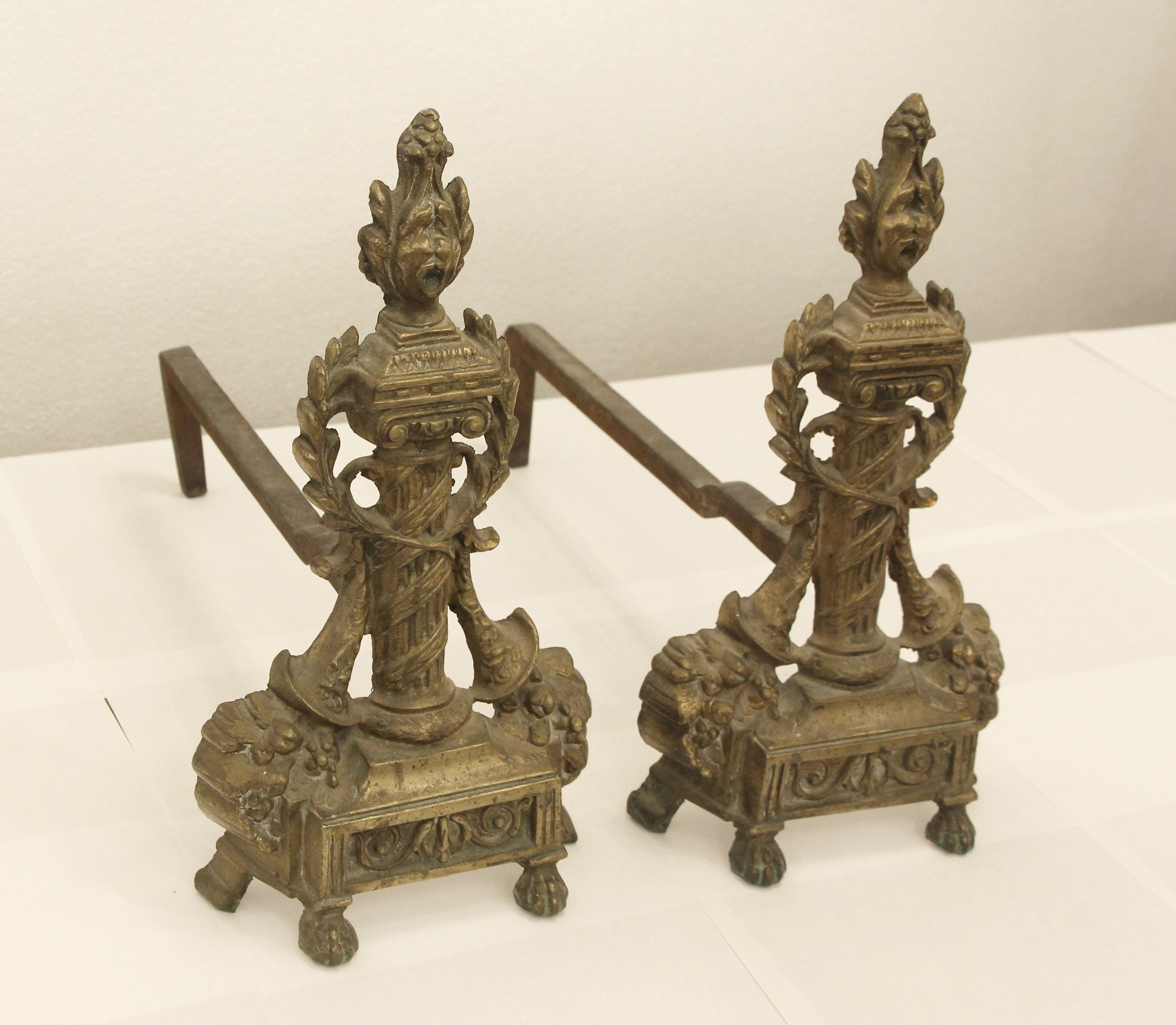 Highly ornate pair of 1940s French style andirons with bronze torch tops and iron dog legs. Sold as a pair. These can be seen at our 302 Bowery location in Manhattan.