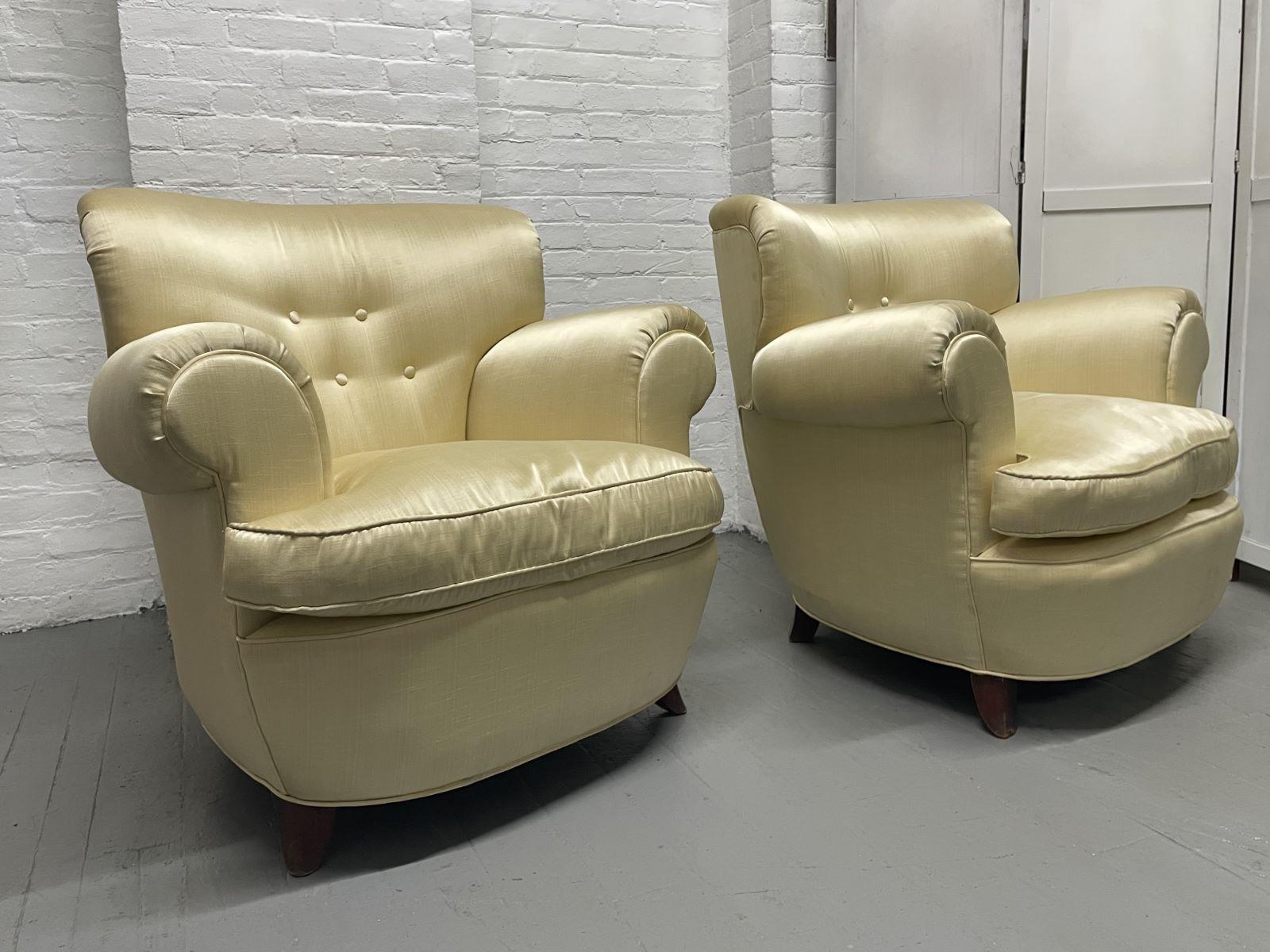 1940s pair of French lounge chairs that are nicely upholstered in silk with rolled arms and loose down filled seat cushions. The chairs have flared mahogany legs.