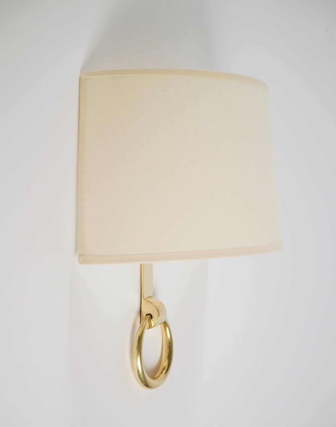 Consists on gilded bronze back plate with a large suspended ring.
Half-moon shaped lampshade in off-white cotton.
Each sconce are signed an numbered .
One bulb per sconce.
 