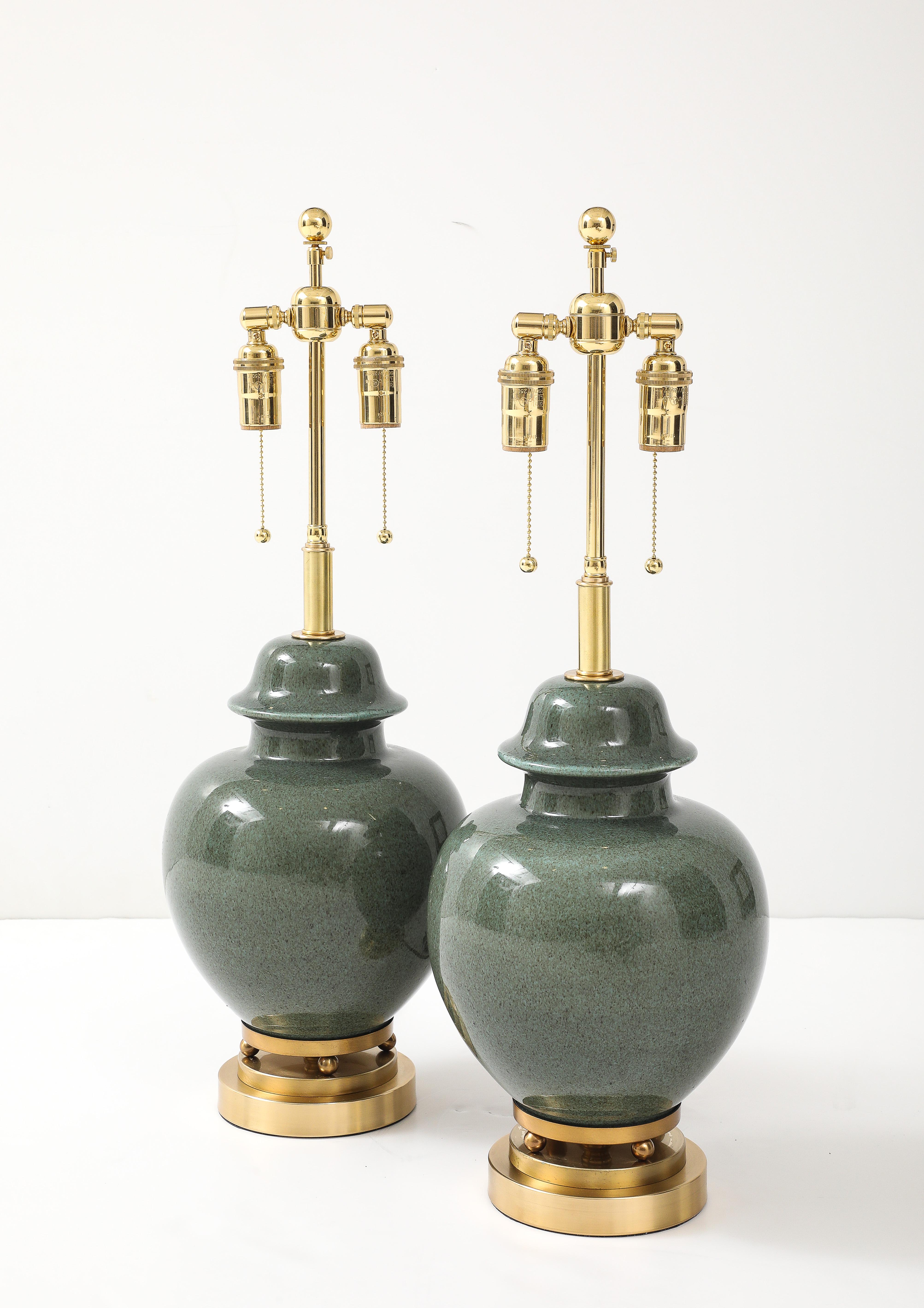 Pair of 1940's ceramic ginger jar lamps with a beautiful Moss green glaze.
The lamps sit up on brass balls and bases, and they have been Newly rewired
with adjustable polished brass double clusters and silk rayon cords.
The height to the top of the