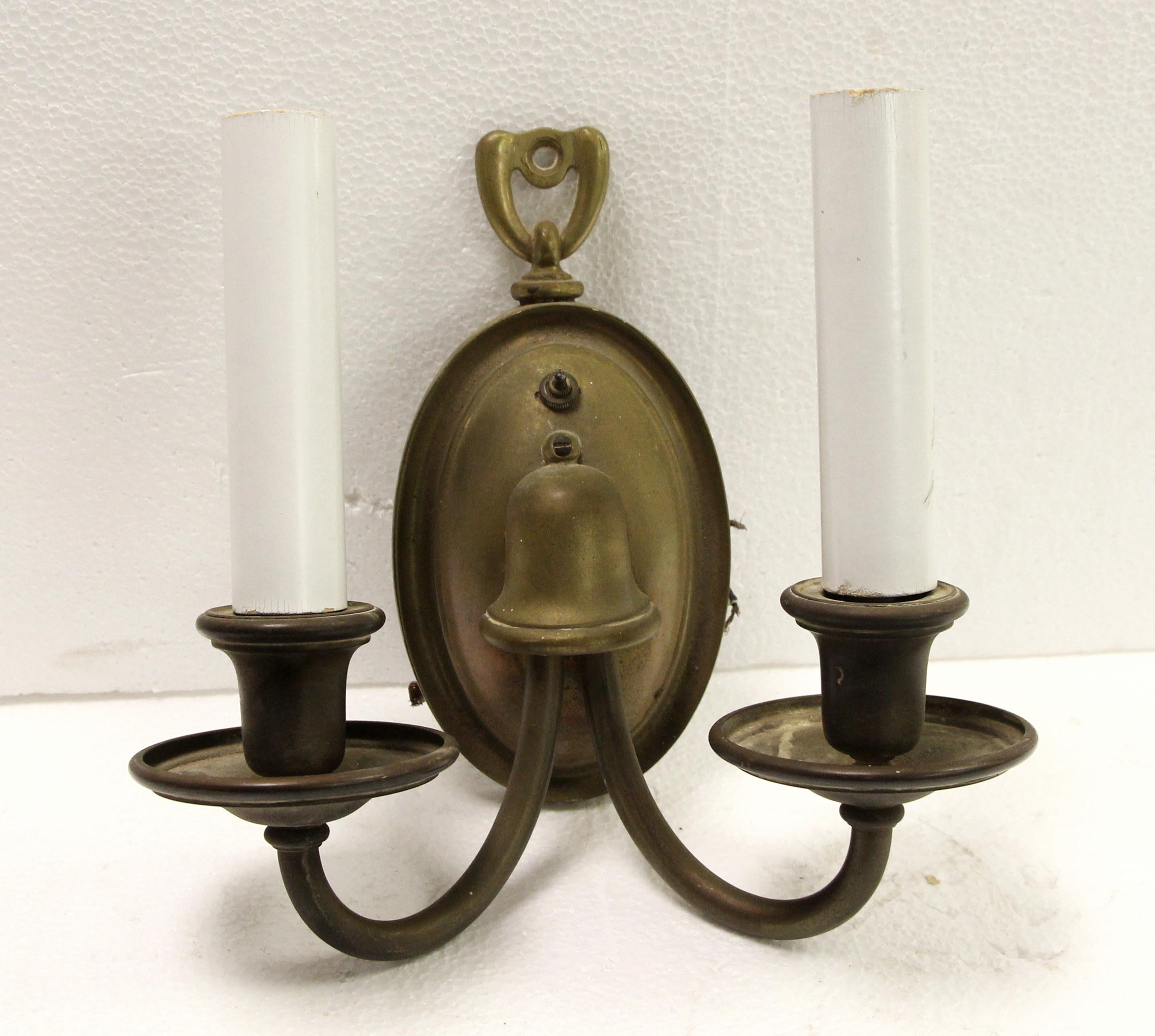 Traditional style brass two arm sconces with an antique patina from the 1940s. Sold as a pair. This can be seen at our 400 Gilligan St location in Scranton, PA. 