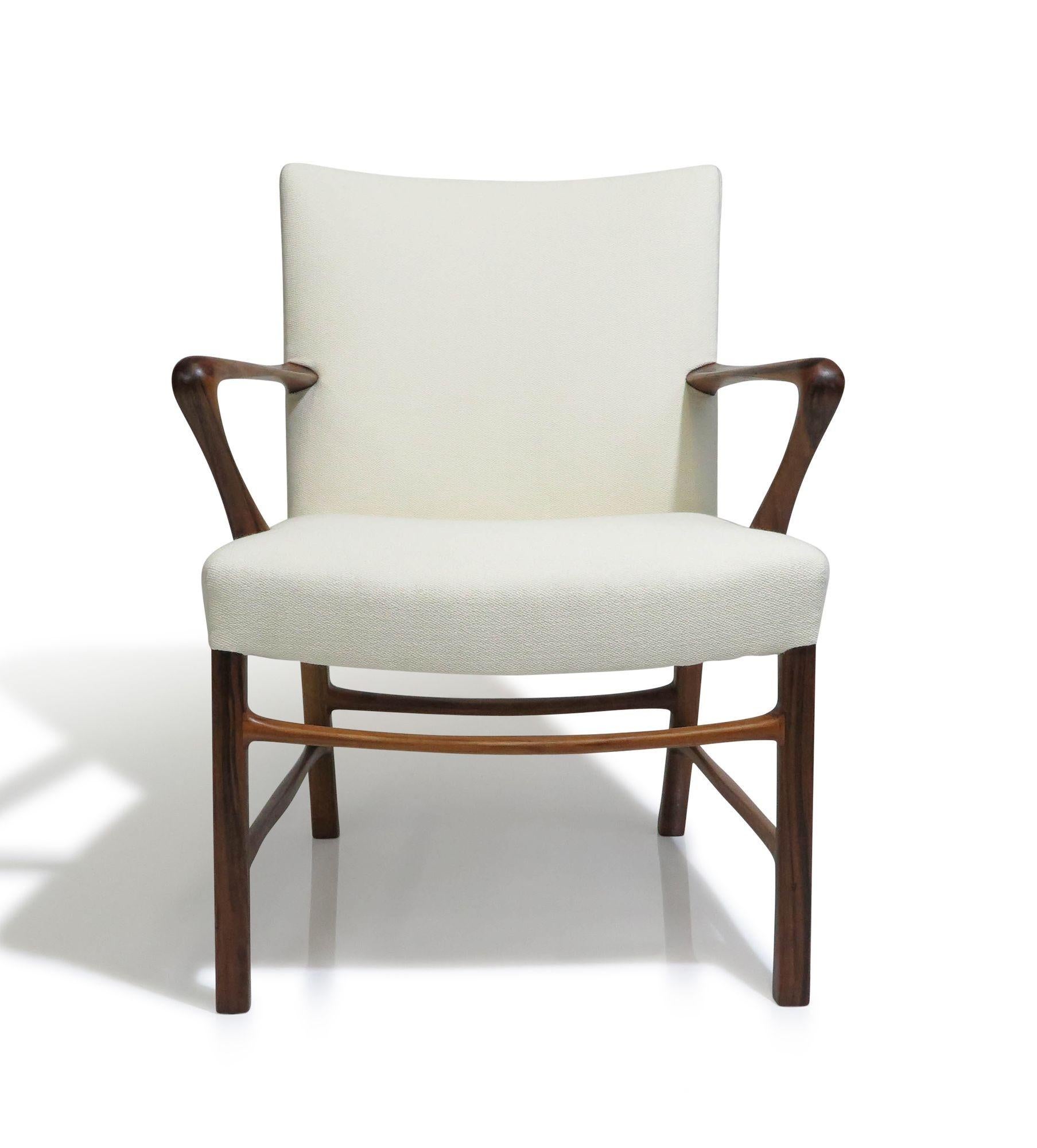 Finely sculpted armchair in rosewood, designed by Danish modernist architect Palle Suenson for Jacob Kjaer, c.1940, Denmark. The chair showcases elegantly curved arms and cross stretchers made of rosewood. It has been newly upholstered in