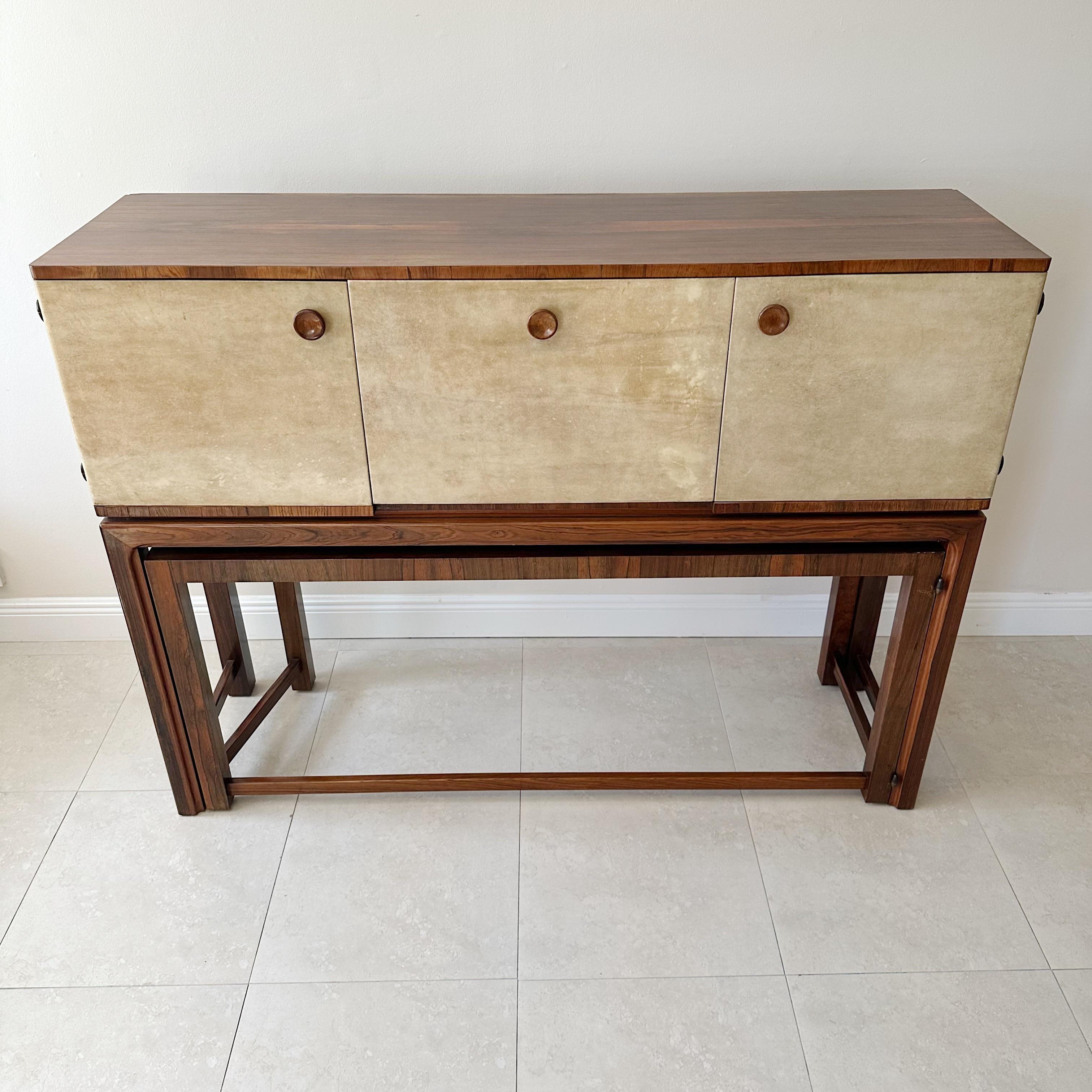 An exceptional chest on stand with a hidden roll-out table that can serve as a bar, server, or even a desk. The chest is crafted from rosewood and parchment and features solid brass bullet hardware. This piece dates back to the 1940s and is in