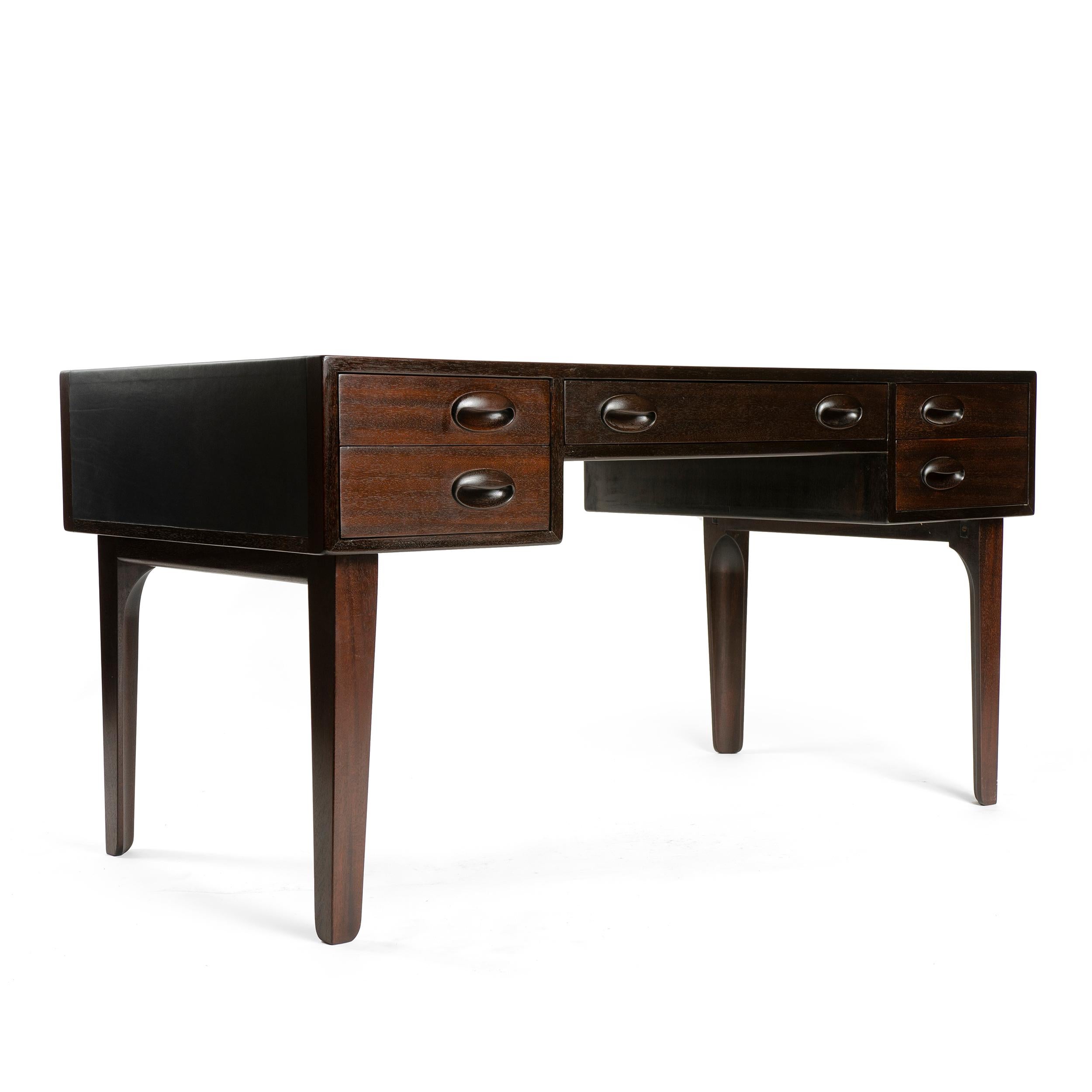 A mahogany partners desk with deep navy leather inset top, four drawers and central compartment with hinged front, over tapered legs.