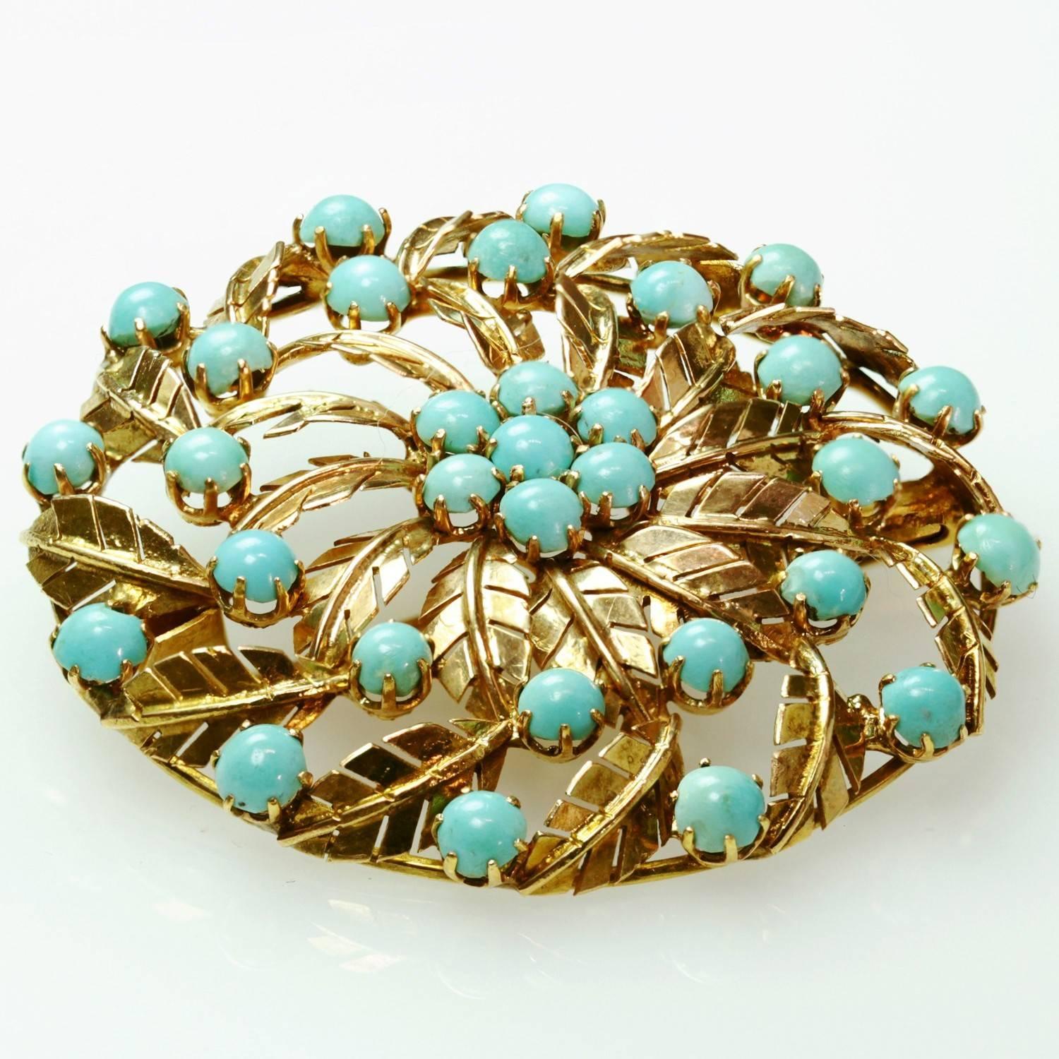 A captivating vintage brooch featuring textured leaves in 18k yellow gold set with natural round turquoise stones in even light blue tones. Circa 1940s. Measurements: 1.53