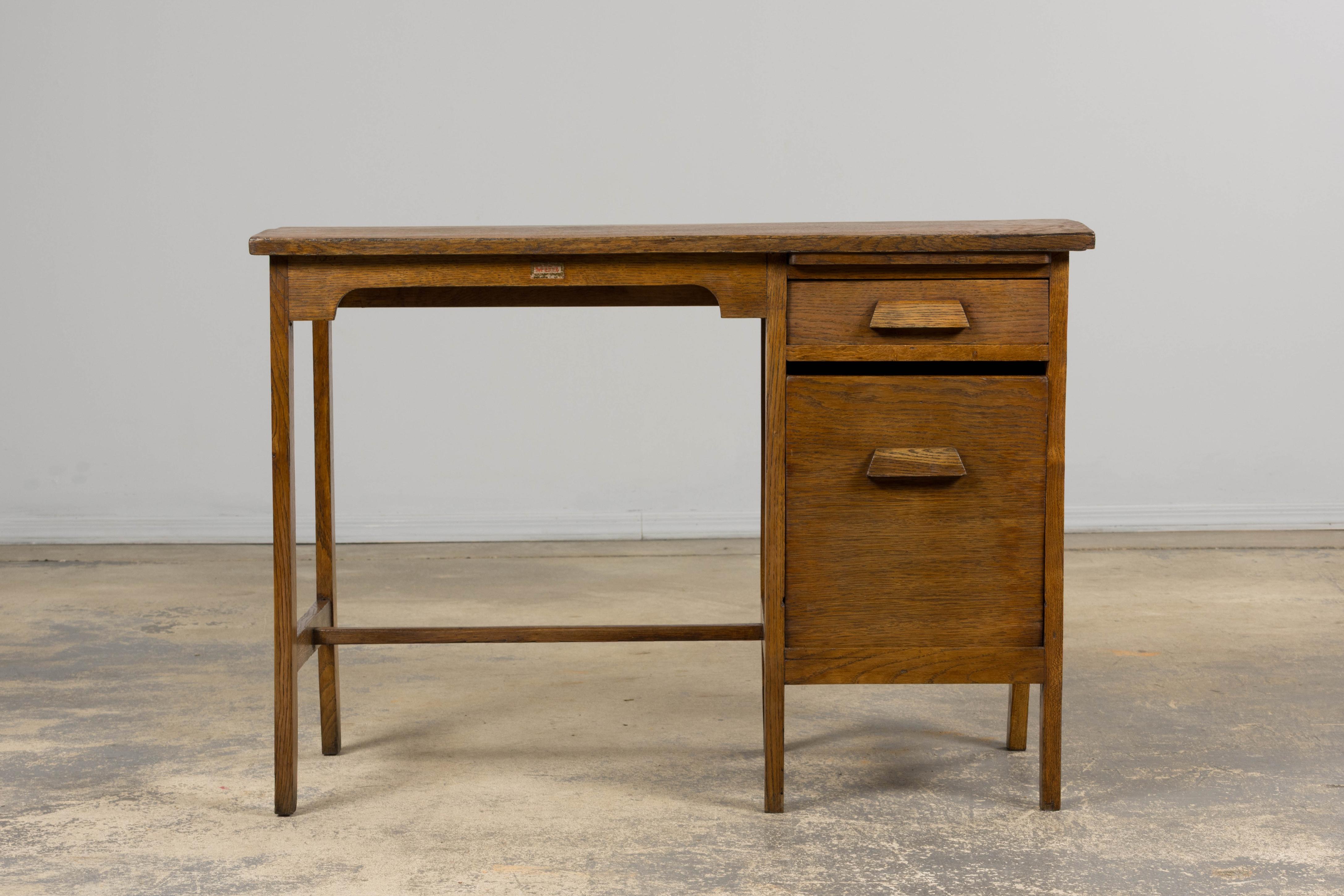 Piccola scrivania da ufficio in rovere francese, anni '30-'40 circa. Restaurata con cura per garantirne l'integrità strutturale, conserva l'autentica patina invecchiata e il movimento naturale della superficie. La forma compatta presenta un piano