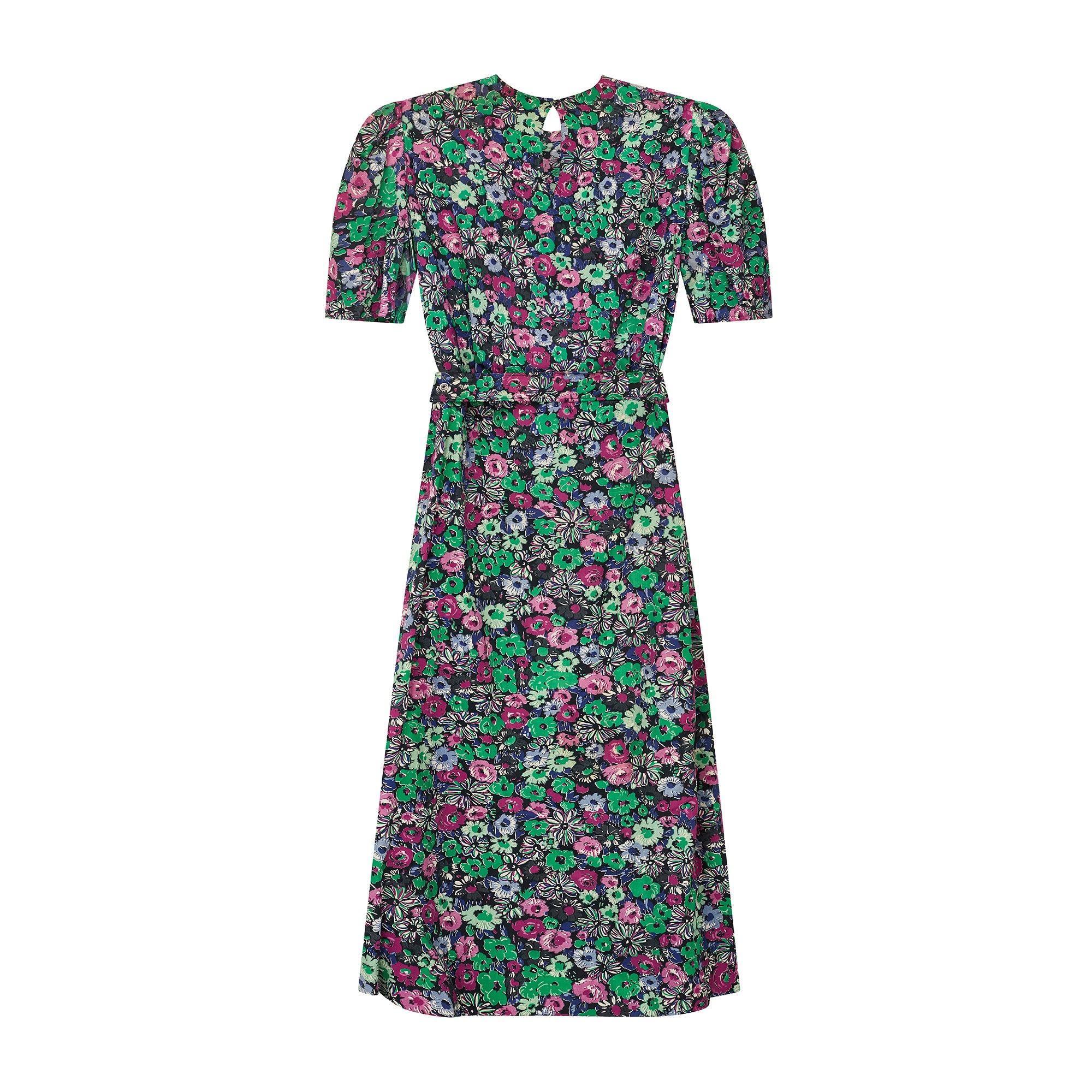 Este bonito vestido midi de rayón de los años 40 tiene estampados florales repetidos en violeta brillante, verde esmeralda y berenjena, sobre un fondo negro carbón que realza los colores. El vestido tiene la forma clásica de un vestido de té de los