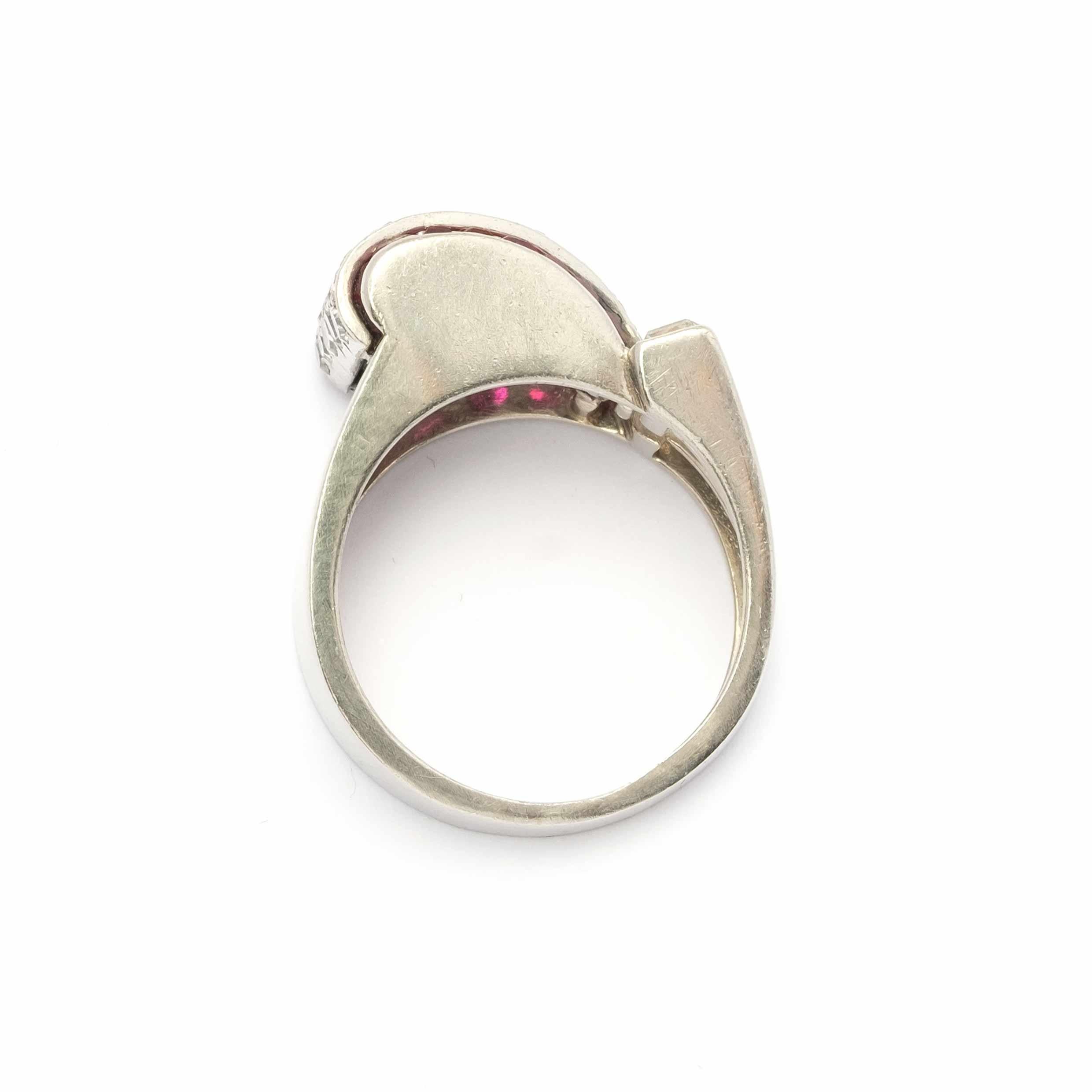 Raffinato anello a ponte degli anni '40, finemente lavorato a mano in platino (marchio 950) e inciso con le iniziali dell'orafo (C.F.). La montatura è impreziosita da rubini naturali calibrati per un totale di circa 0,20 carati, abbinati a diamanti