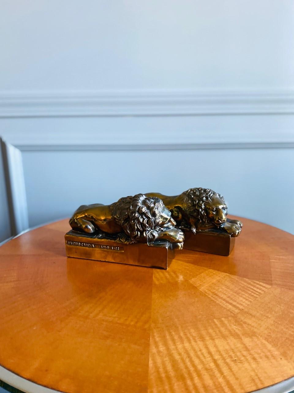 Pair of 1940s polished bronze plated metal lion bookends. Signed: “Antonio Canova. 1757-1822.” These lions were originally sculpted by Antonio Canova (Italian, 1757-1822) in larger scale for the tomb of Pope Clement XIII in St. Peter’s Basilica. The