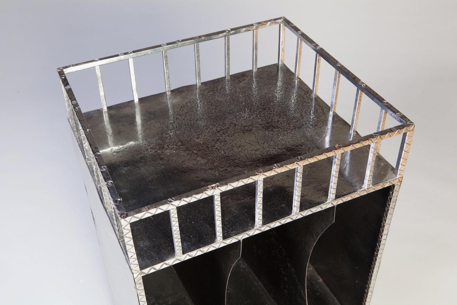 France, circa 1945

A modernist polished steel Canterbury end table. The gallery decorated with cross hatching and punching. The three slides have a shelf below and the whole stands on scroll legs.

Measures: Height 29 in (74 cm)
Width 19 in