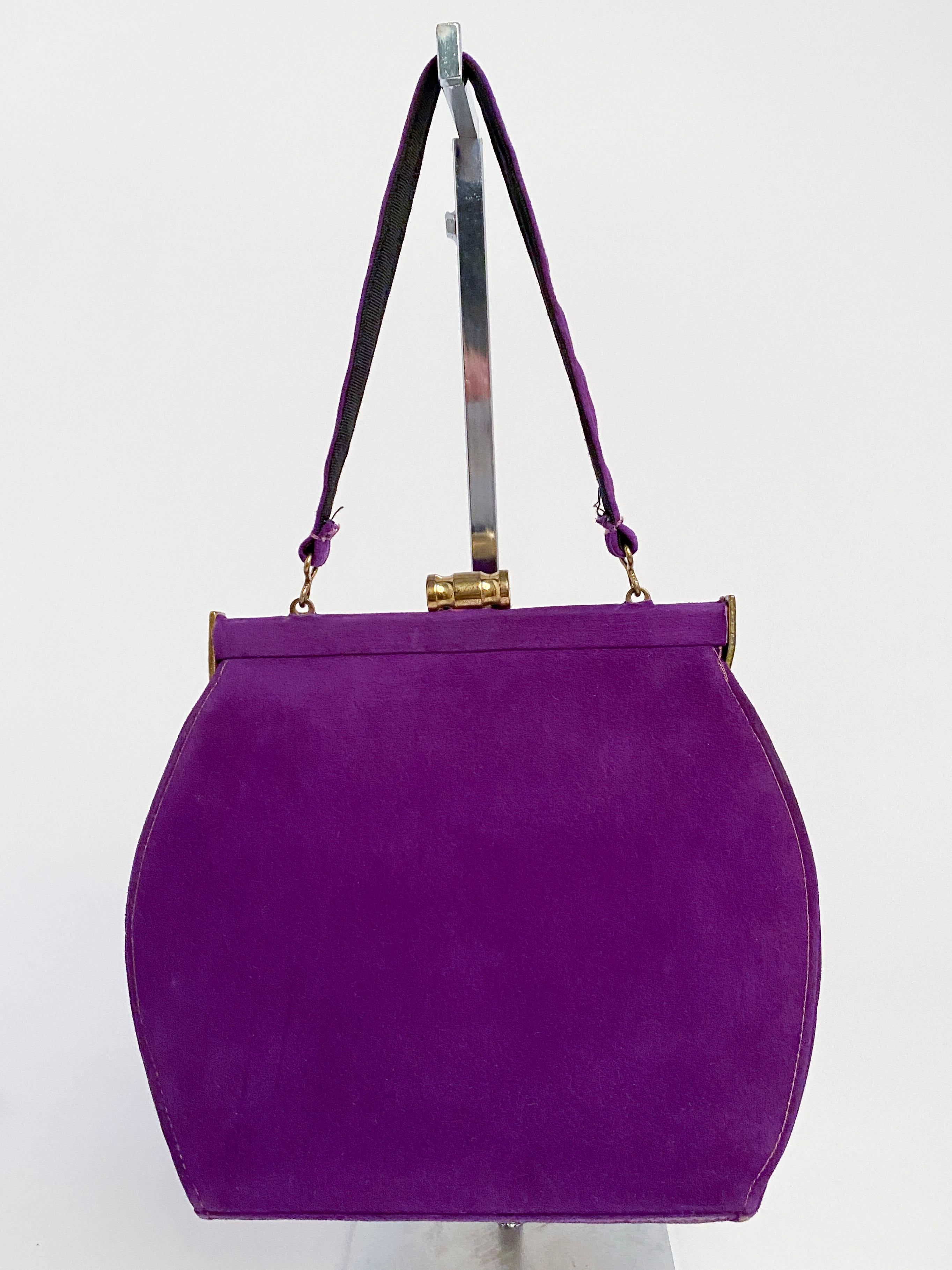 1940s purple suede handbag with matching suede handle and adorned with brass hardware and closure. Interior lining is made of a black twill with one interior pocket.