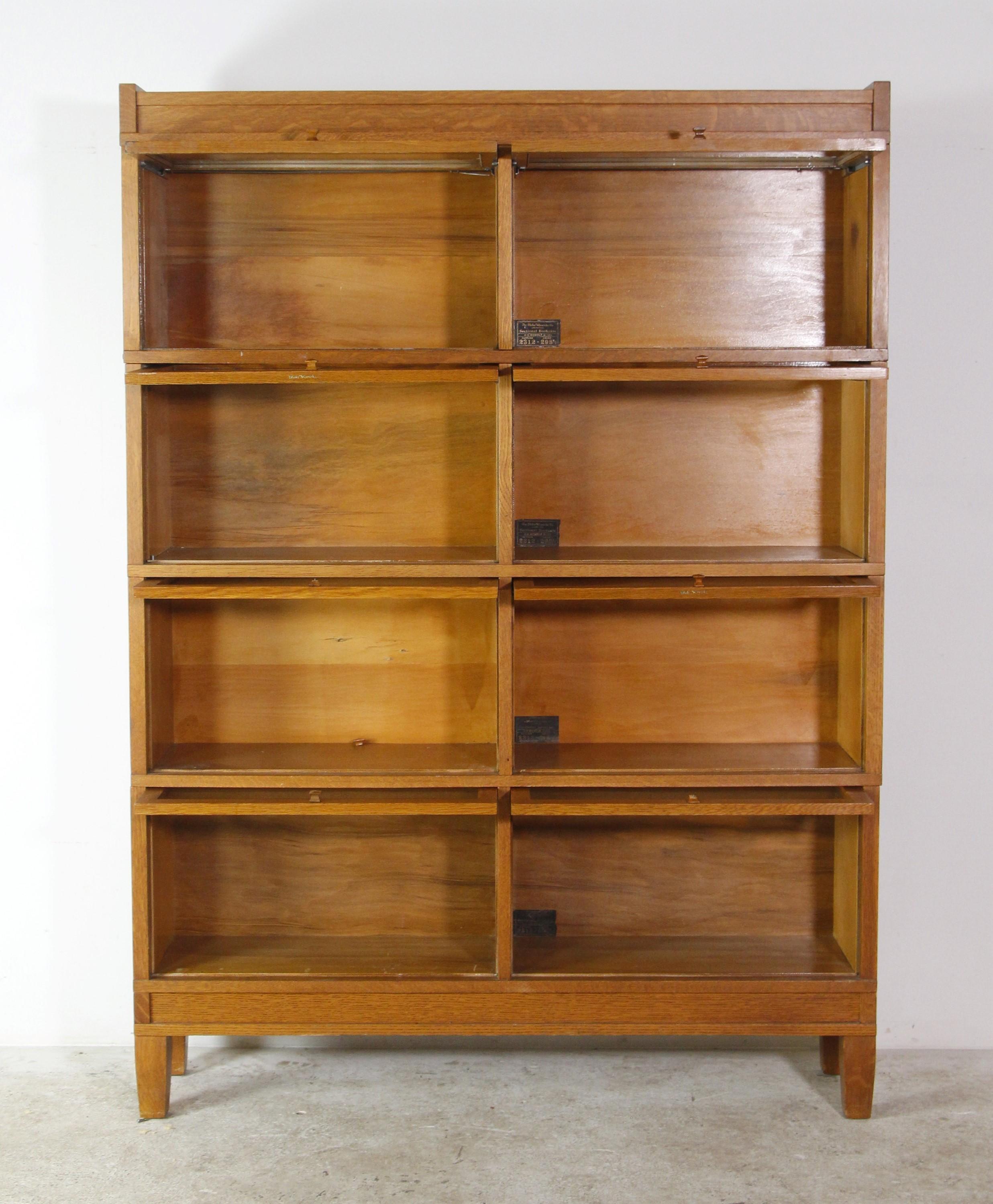 This antique double sectional bookcase is made of quarter sawn oak and has eight sections each with a glass front cover. Each section opens with an Arts and Crafts style wooden knob. Manufactured in the 1940's by the Globe-Wernicke Co. This