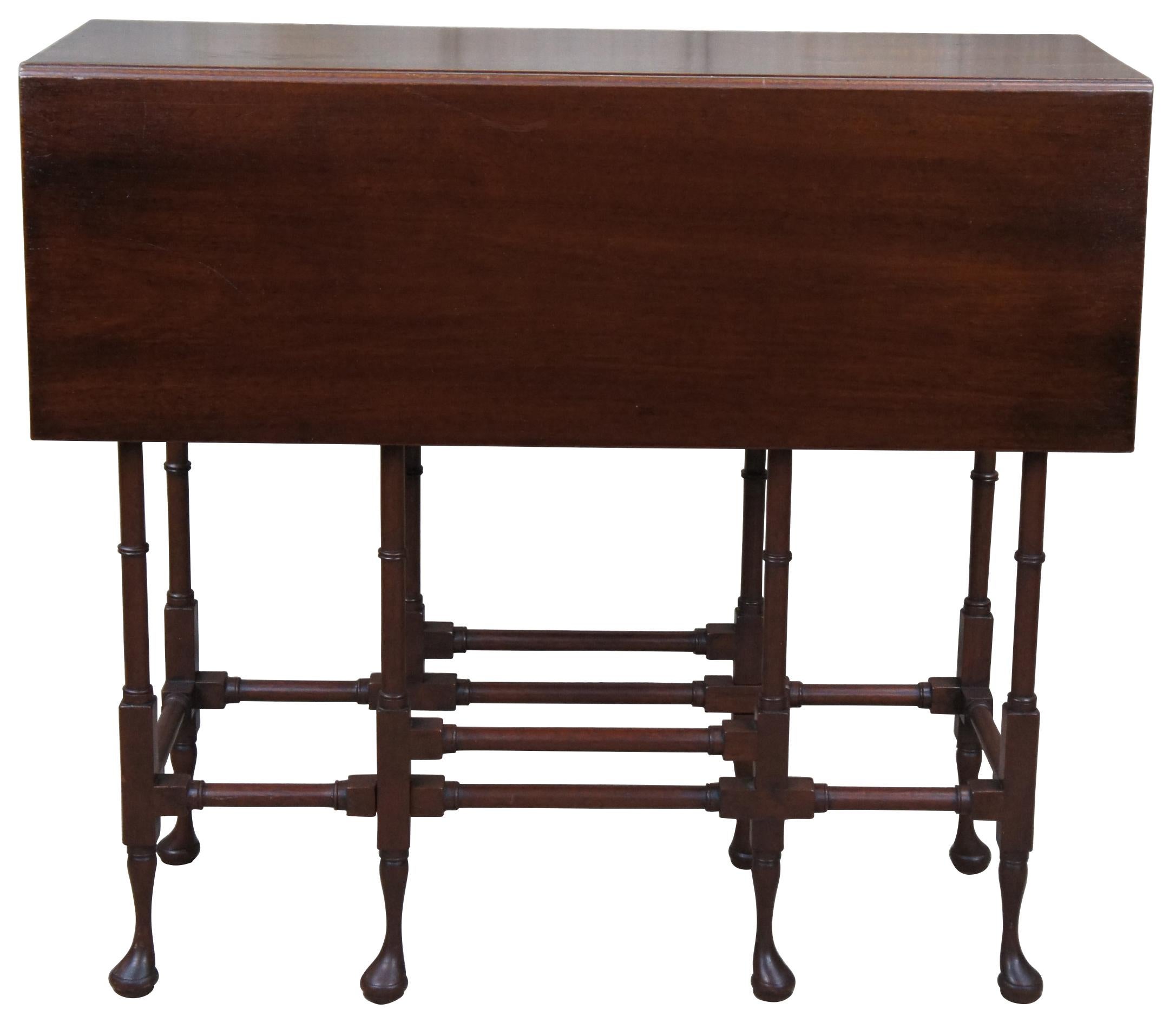 A classic and petite George III mahogany drop leaf side table from the legendary Chicago furniture maker, Quigley, circa 1940s. Features a long and slender form with central drawer, split drop leaf along one side and spider campaign style legs.