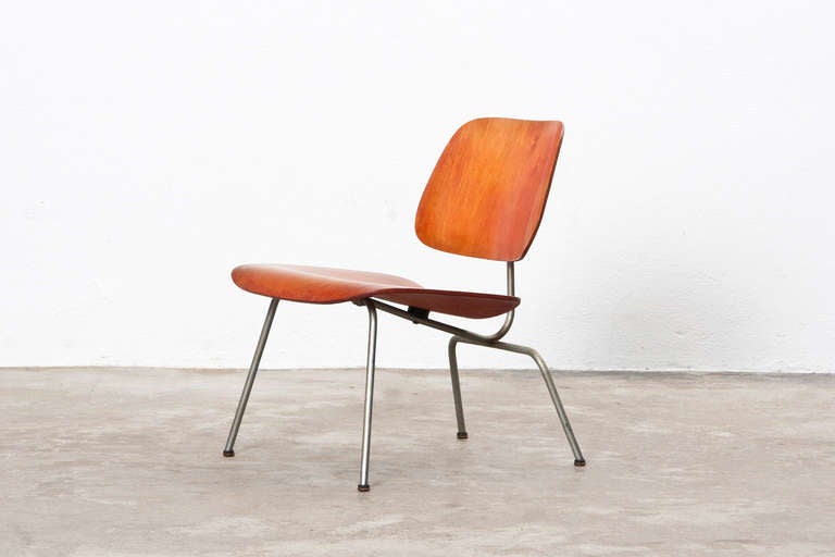 Early example of LCM chair designed by Charles and Ray Eames. This 1951 LCM has its original red aniline dye finish, chrome finish legs, and domes of silence glides. Manufactured by Evans.

Together with his wife Ray Eames (1912–1988) he