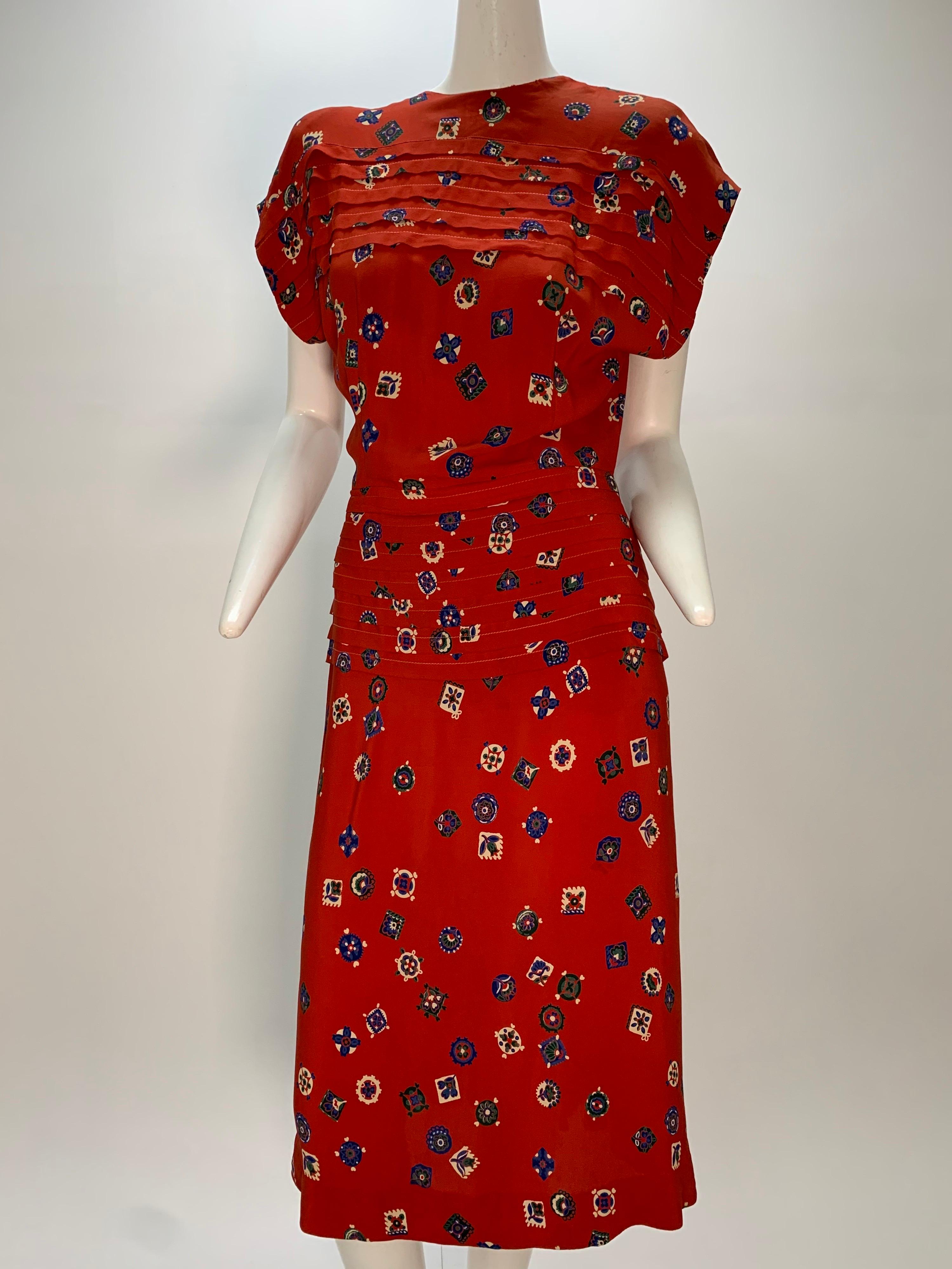A sweet 1940s red crepe novelty calico-style print rayon swing dress with sewn-down pleated peplum, drop-shoulder and flared skirt back details. Original shoulder pads. Zip at back. Mid-calf length. 