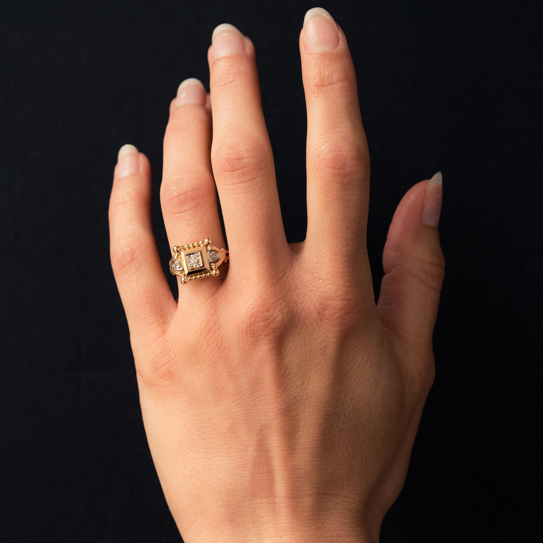 Ring in 18 karat rose gold, eagle's head hallmark.
With a square tray, it is set in the center of a diamond. The set is bordered with gold pearls, those at the corners being larger. The start of the ring is composed of a double gold ribbon which