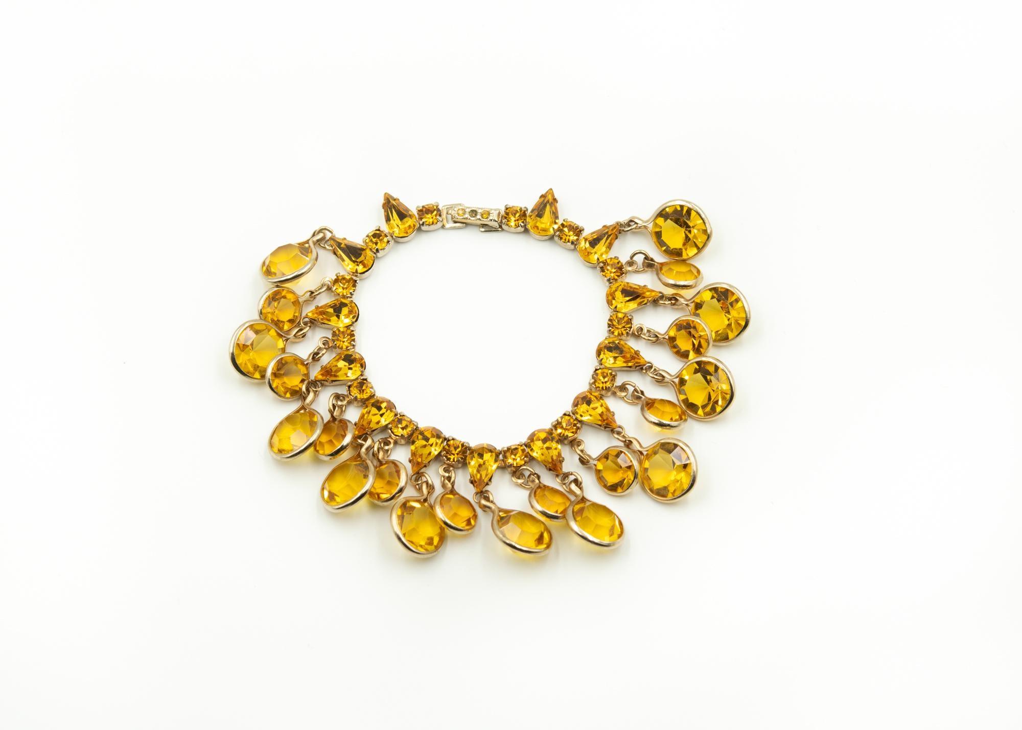 Fantastic fun 1940's Kramer dangling dancing citrine drop earrings and bracelet demi-parure.  

The top section of the bracelet features pear shape prong set citrine colored rhinestones with prong set rounds between them.  Dangling from the above