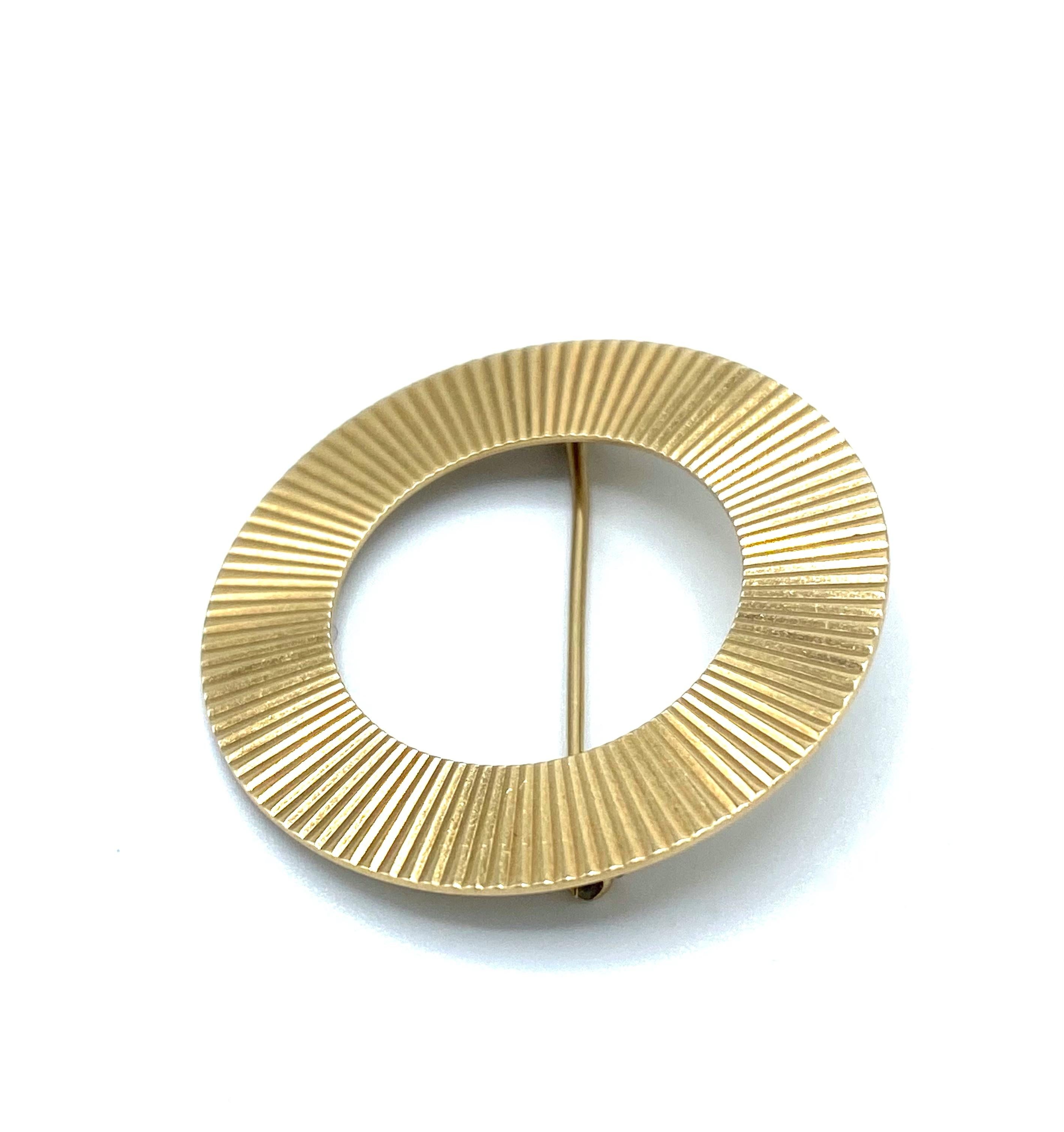 Product details:

The brooch is designed by Tiffany and Co. It is made out of 14 karat yellow gold with striped pattern finish.

Measurements: the diameter is 1.25