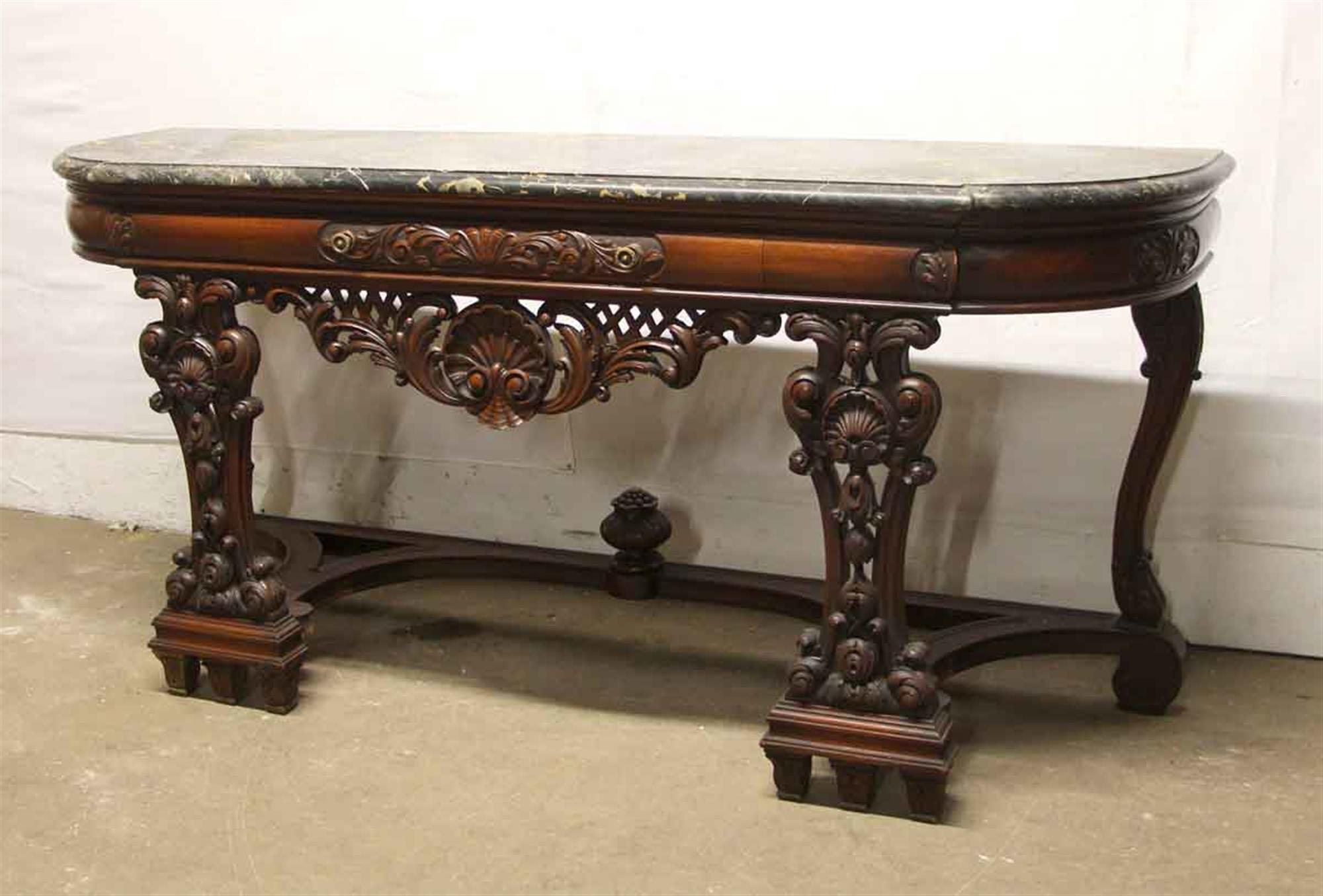 Rococo style intricately carved dark wood tone entry table with a solid black and golf colored marble top, circa 1940s. This is in excellent condition. Made by The Leonardo Co., Inc. NY. This can be seen at our 400 Gilligan St location in Scranton,