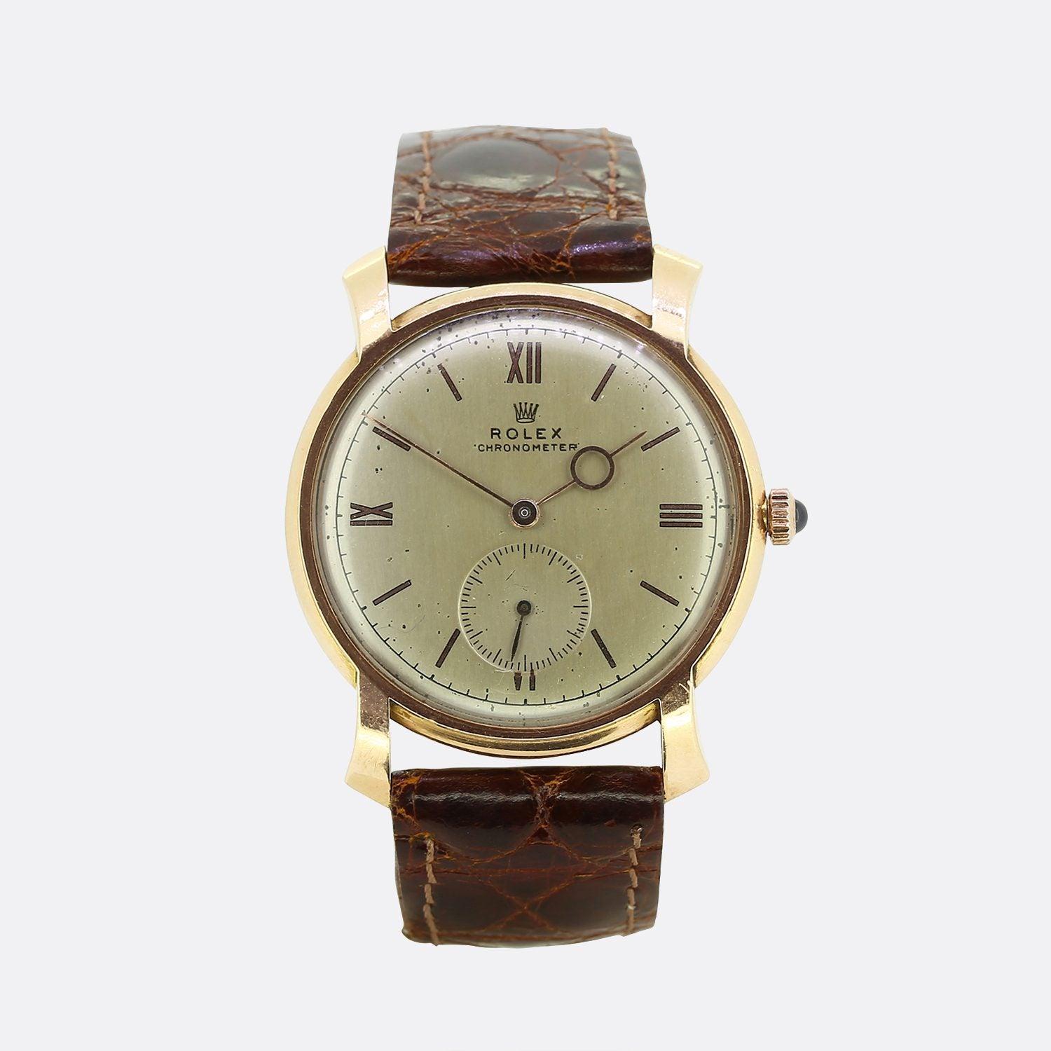 Il s'agit d'une montre Rolex Chronomètre unisexe en or jaune 14ct des années 1940. Le cadran est de couleur blanc cassé, avec des aiguilles en or rose et des index en chiffres romains à 12, 3, 6 et 9 heures. La montre porte la signature 