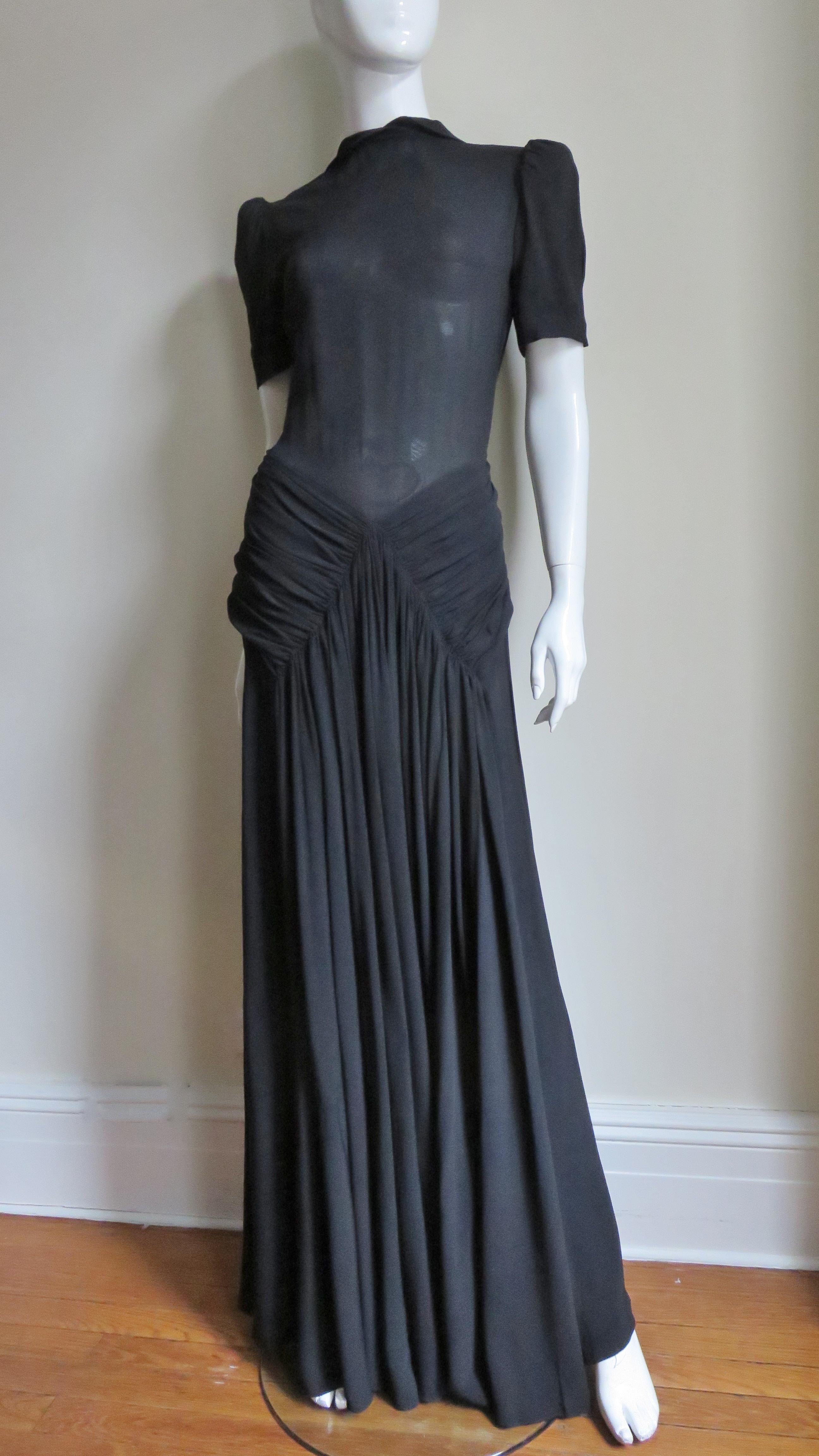 A gorgeous black silk 1940's maxi dress with an interesting interplay of demure and sexy.  It has a small peter pan collar and puff short sleeves. The bodice is semi fitted- plain in the front and rows of small vertical tucks starting at each
