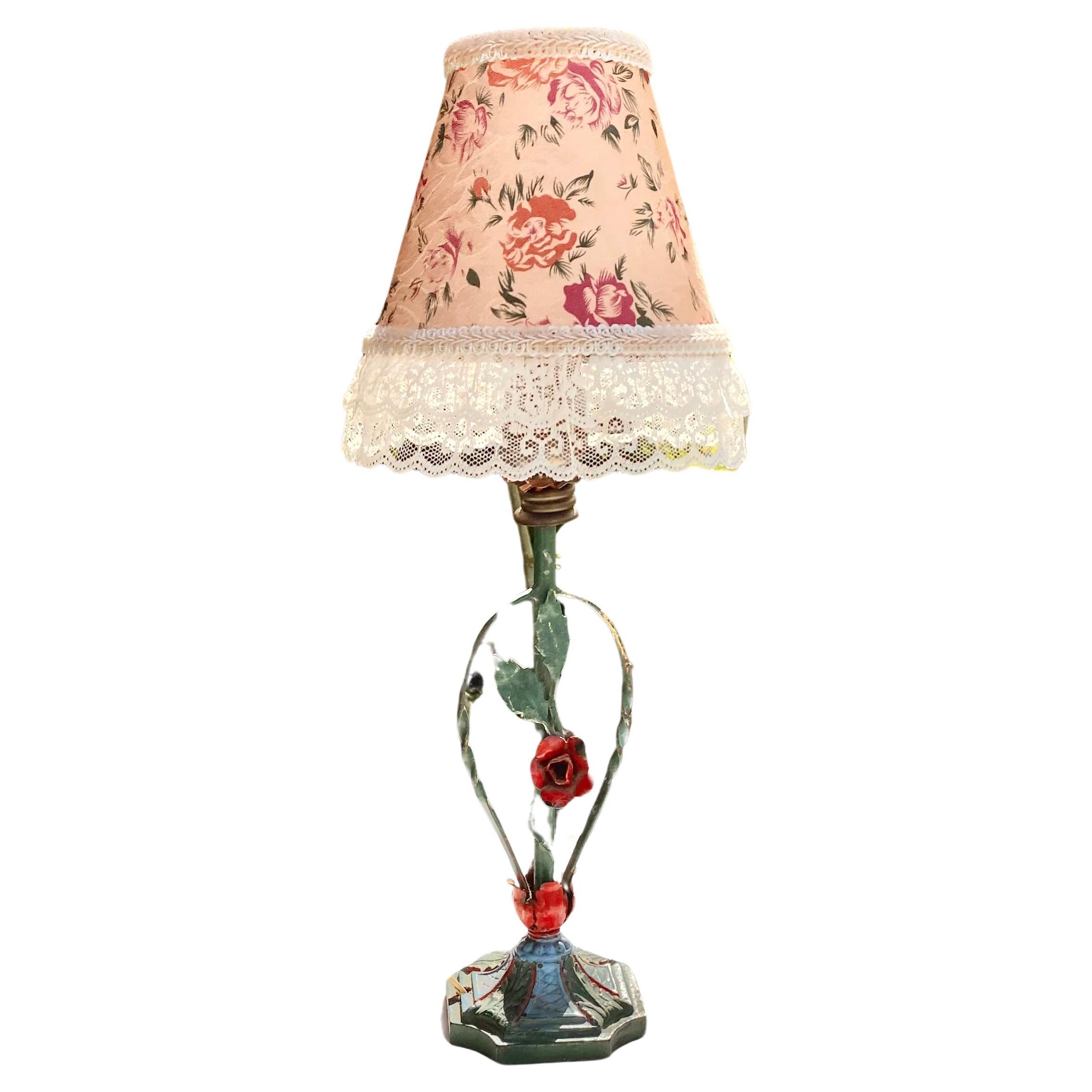 A vintage 1940’s Flower tole lamp with an embossed floral hardback clip on shade with lovely lace and gimp trim. This lamp could work in so many places in so many styles of rooms. Simply classic! Cast iron painted base leads to a lovely red flower