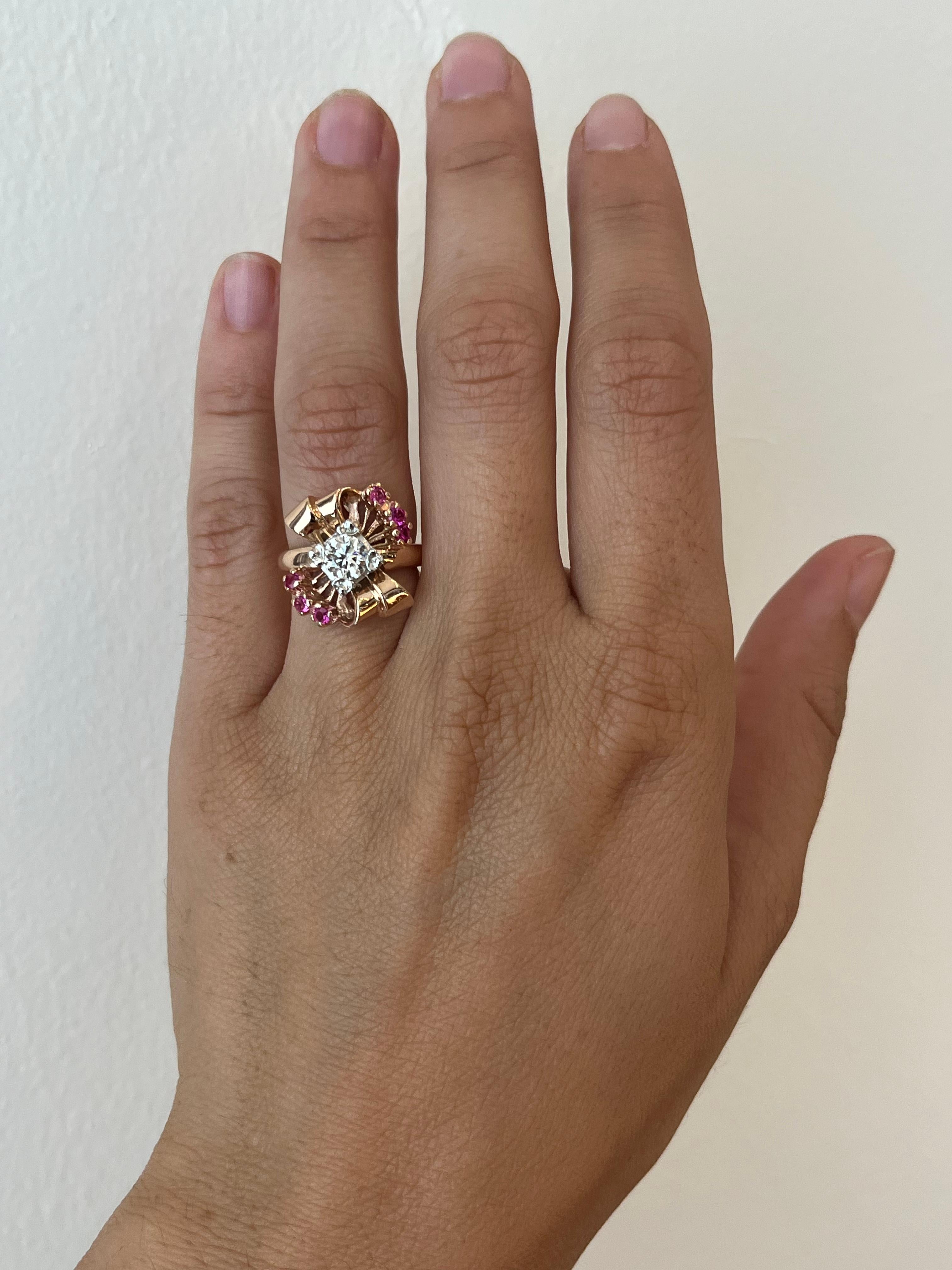 Un autentico anello vintage degli anni '40 in oro rosa 14K con un diamante centrale da 0,43 carati e sei piccoli rubini. Il design decorativo presenta elementi floreali, fiocchi e scoppi.

- 0,43 carati di diamante naturale antico taglio europeo,