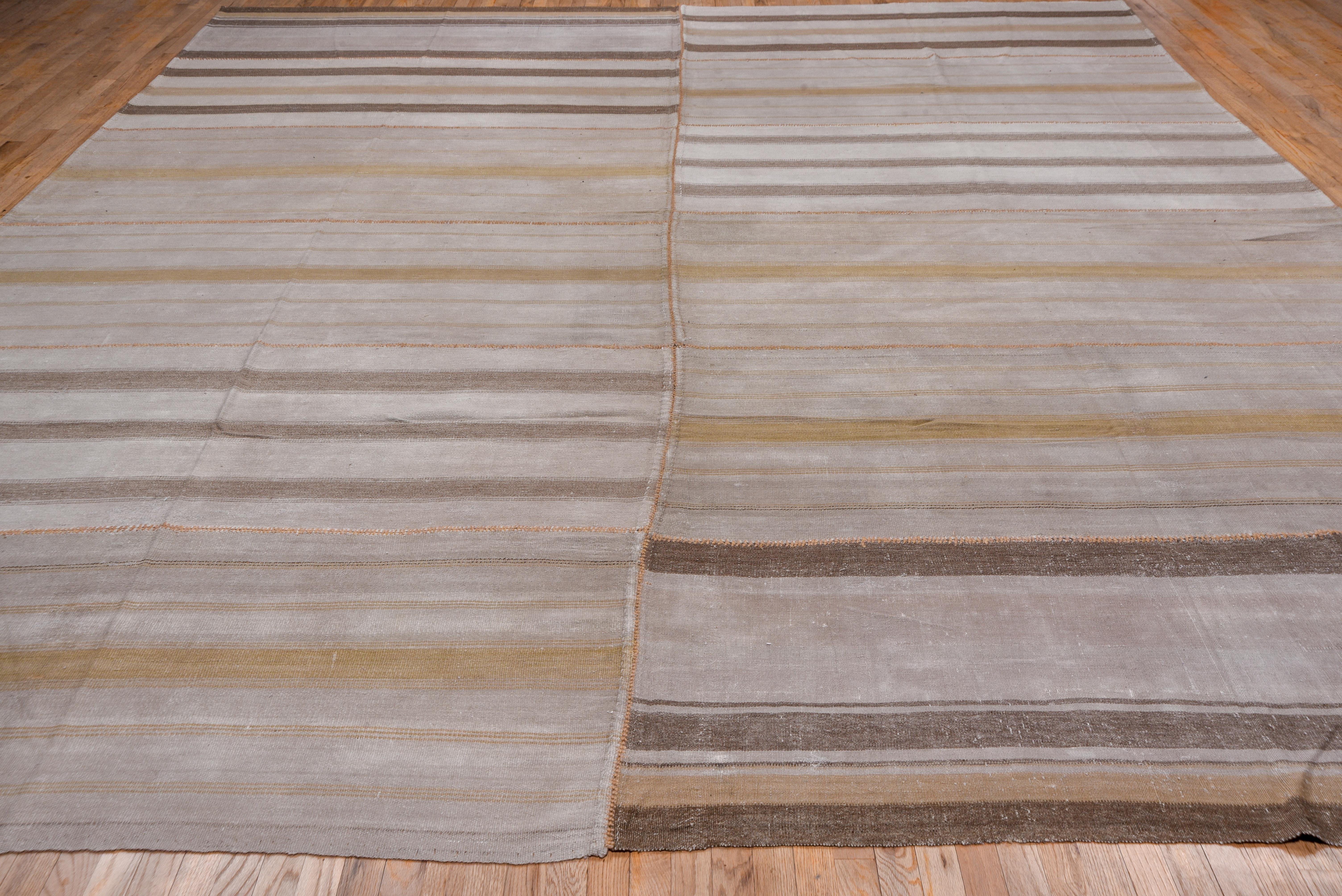 This all wool rustic piece has been created from two edge joined assembled wool panels with jogged stripe designs in shades of brown, beige, straw and taupe. The composite sections were originally parts of long strips, but there is no match that