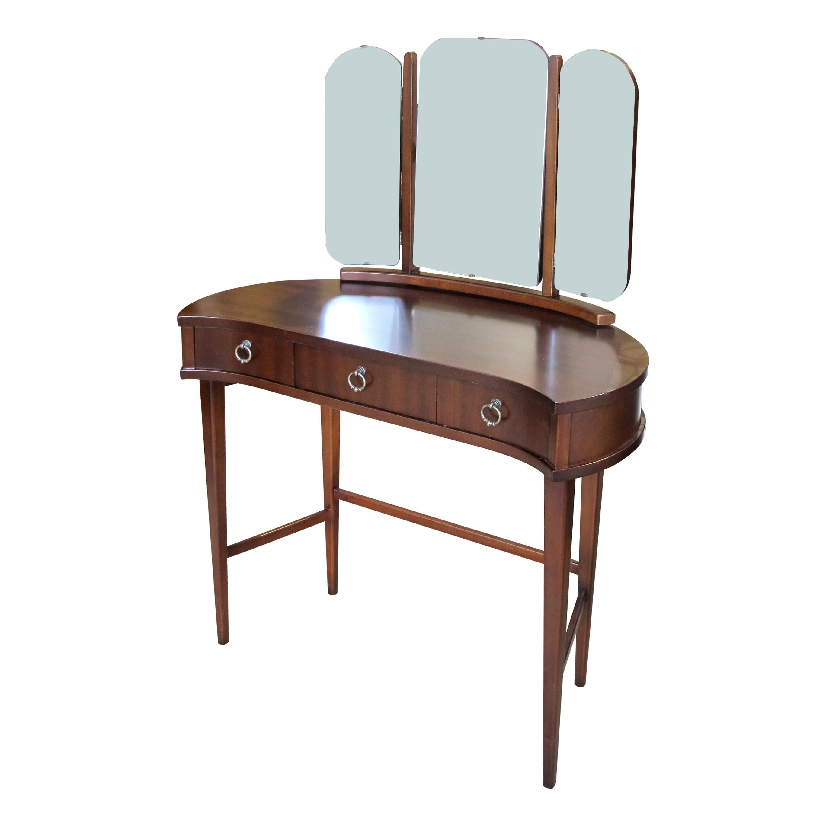 A 1940s Scandinavian dressing table with its triptych mirror and its original handles. The dressing table has a set of 3 drawers, the side mirrors swivel inward and outward and the central mirror swivels up and down. This is a very well-made,
