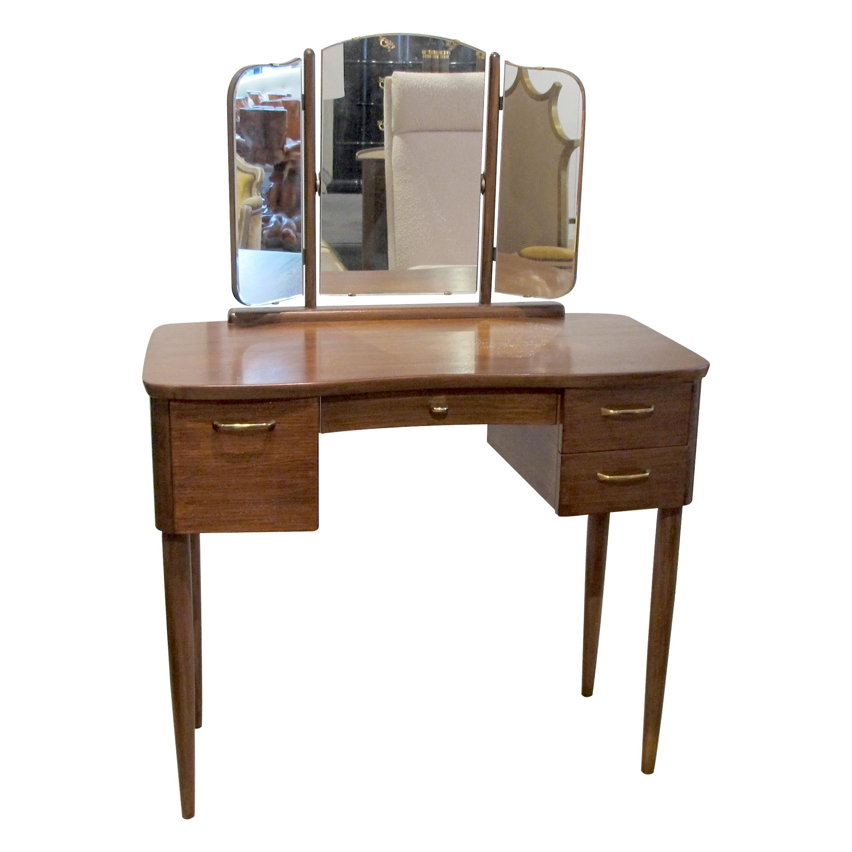 A 1940s Scandinavian dressing table with a triptych mirror and its original brass handles. The dressing table has two identical drawers on the right and a deep single drawer on the left and a shallow central drawer. This is a very well-made, compact