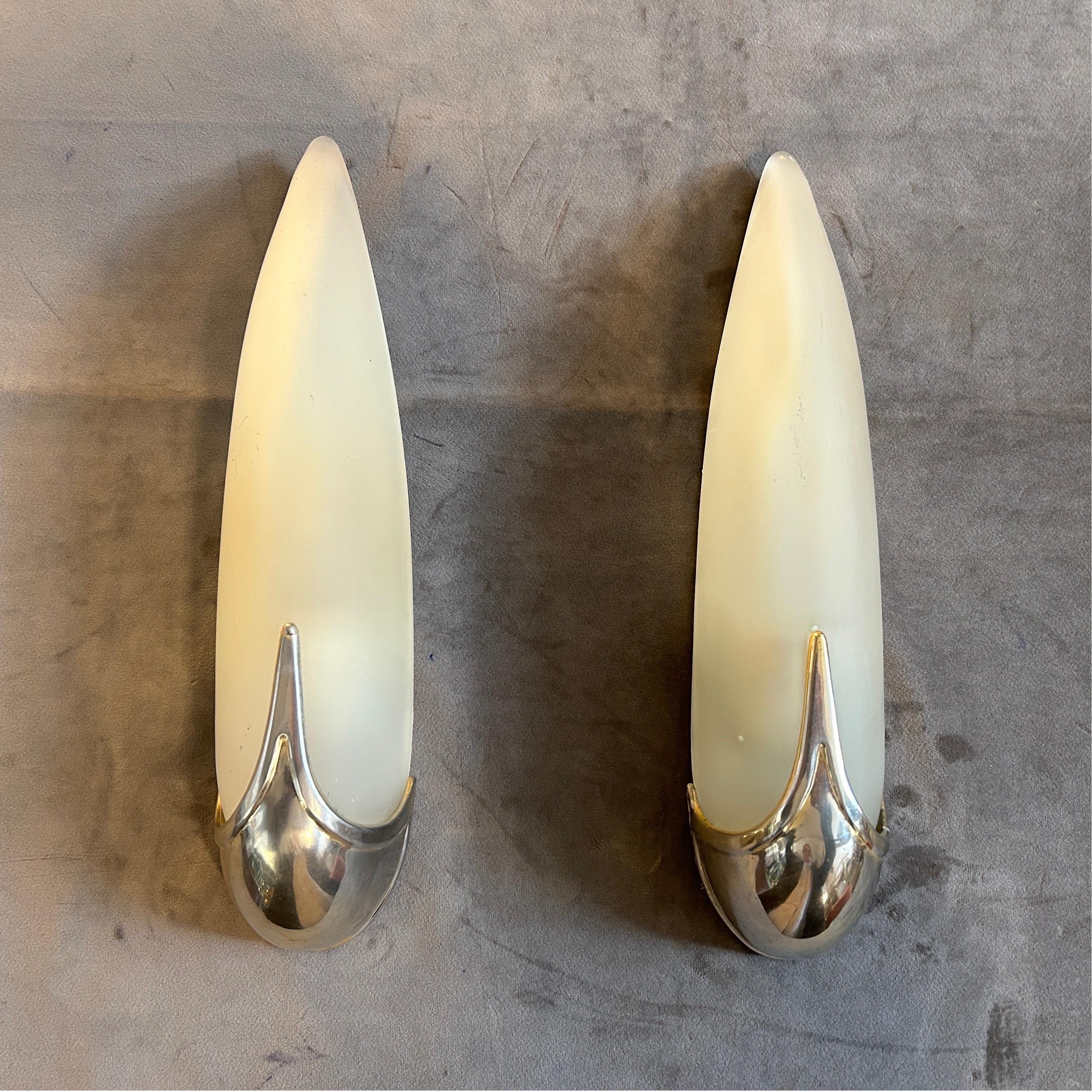 The Set of Two Art Deco Metal and Glass Italian Wall Sconces is a vintage lighting fixture that combines both metal and glass materials in an Art Deco style. The sconces were likely manufactured in Italy during the 1940s, and were designed to be