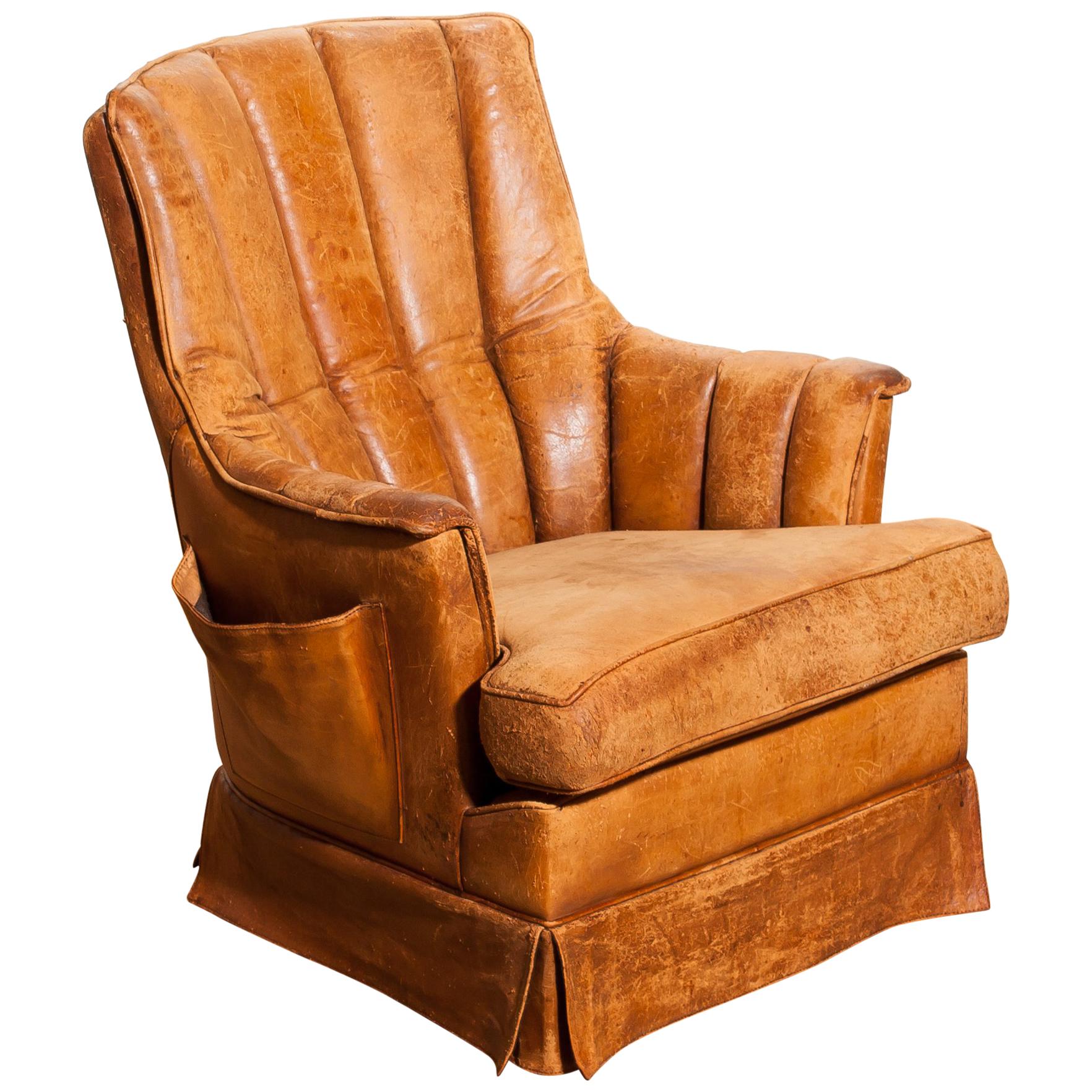 Fantastic club armchair from France.
This chair is made of leather with a skirt and a magazine bag on its side.
It has a greatly used patina.
Period 1940s.
Dimensions: H 85 cm, W 75 cm, D 68 cm, SH 46 cm.