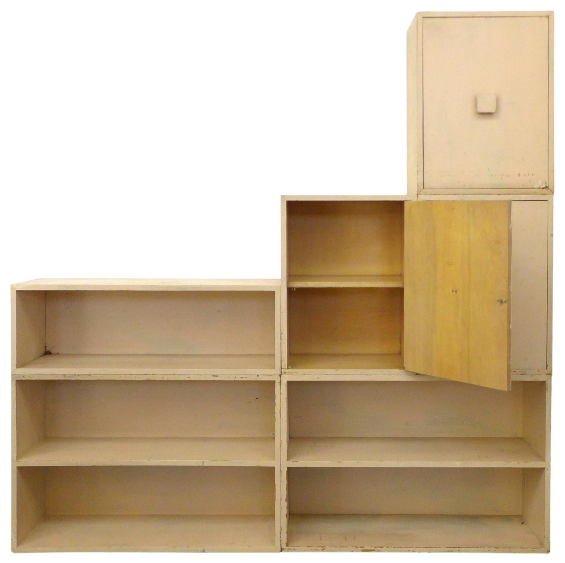 A wonderful 6-piece, modular shelving storage cabinet. Simple, well-built open box shelves and cabinets that can stack in a variety of ways. Currently in a mottled cream, they've been painted several times over the years, resulting in a fantastic