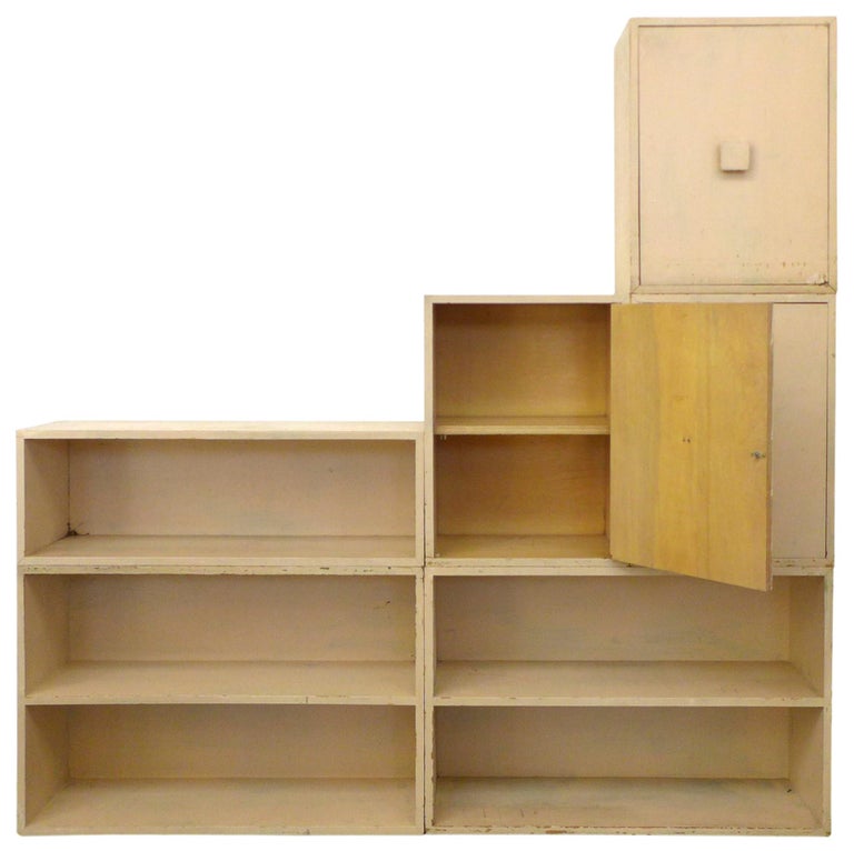 A wonderful 6-piece, modular shelving storage cabinet. Simple, well-built open box shelves and cabinets that can stack in a variety of ways. Currently in a mottled cream, they've been painted several times over the years, resulting in a fantastic