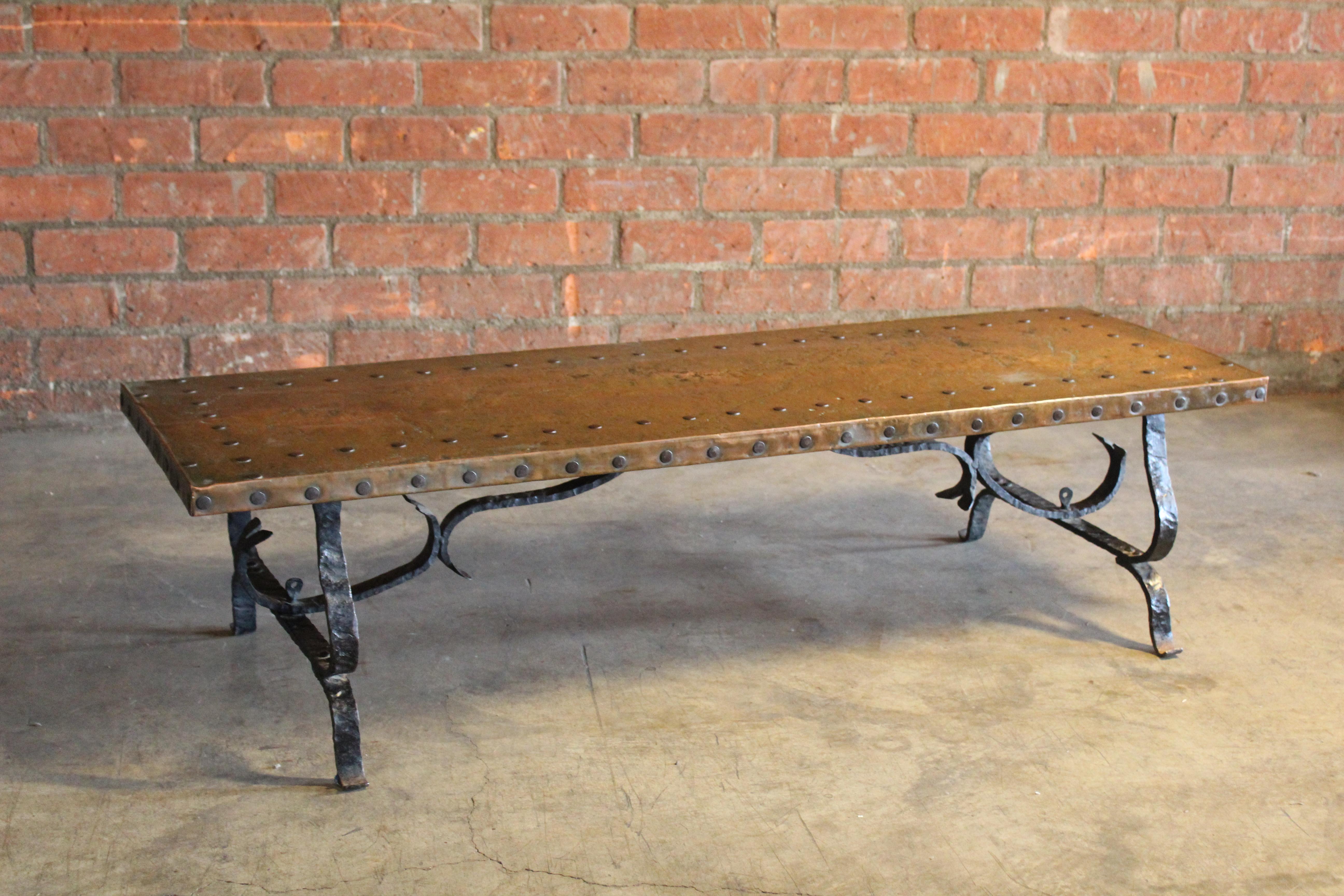 A vintage 1940s coffee table from Spain with a copper clad top on a forged iron base. In good condition with patina and age.