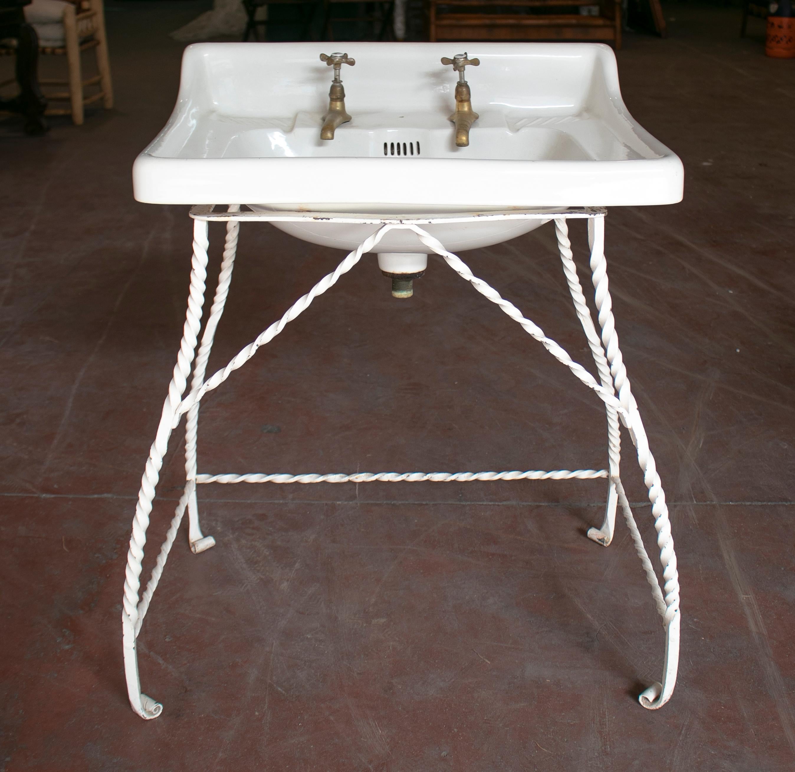 1940s Spanish porcelain wash basin with bronze taps and iron stand.