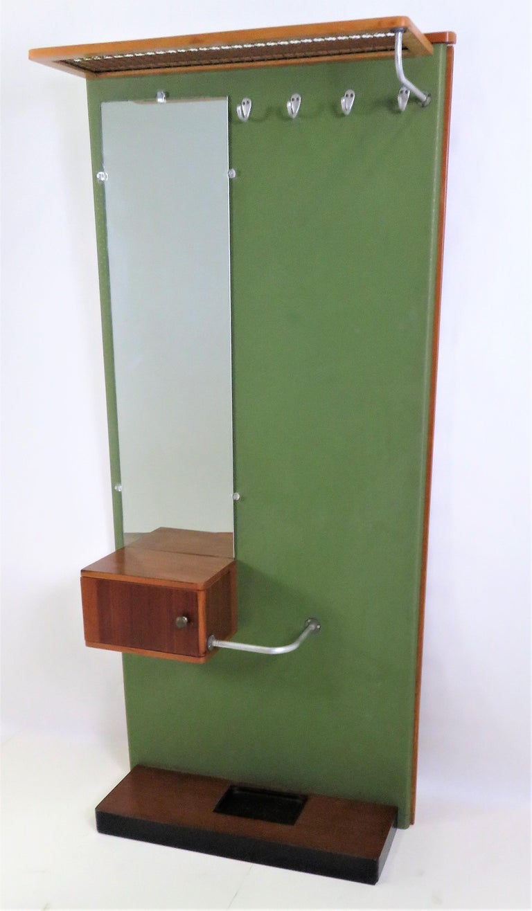 Quite nice Streamline Moderne Halltree with a mirror, hat rack and hooks for over coats and such. Having an umbrella rack and a small cabinet for incidentals, keys and the like. Original green vinyl with a pattern of very small stars. Woods