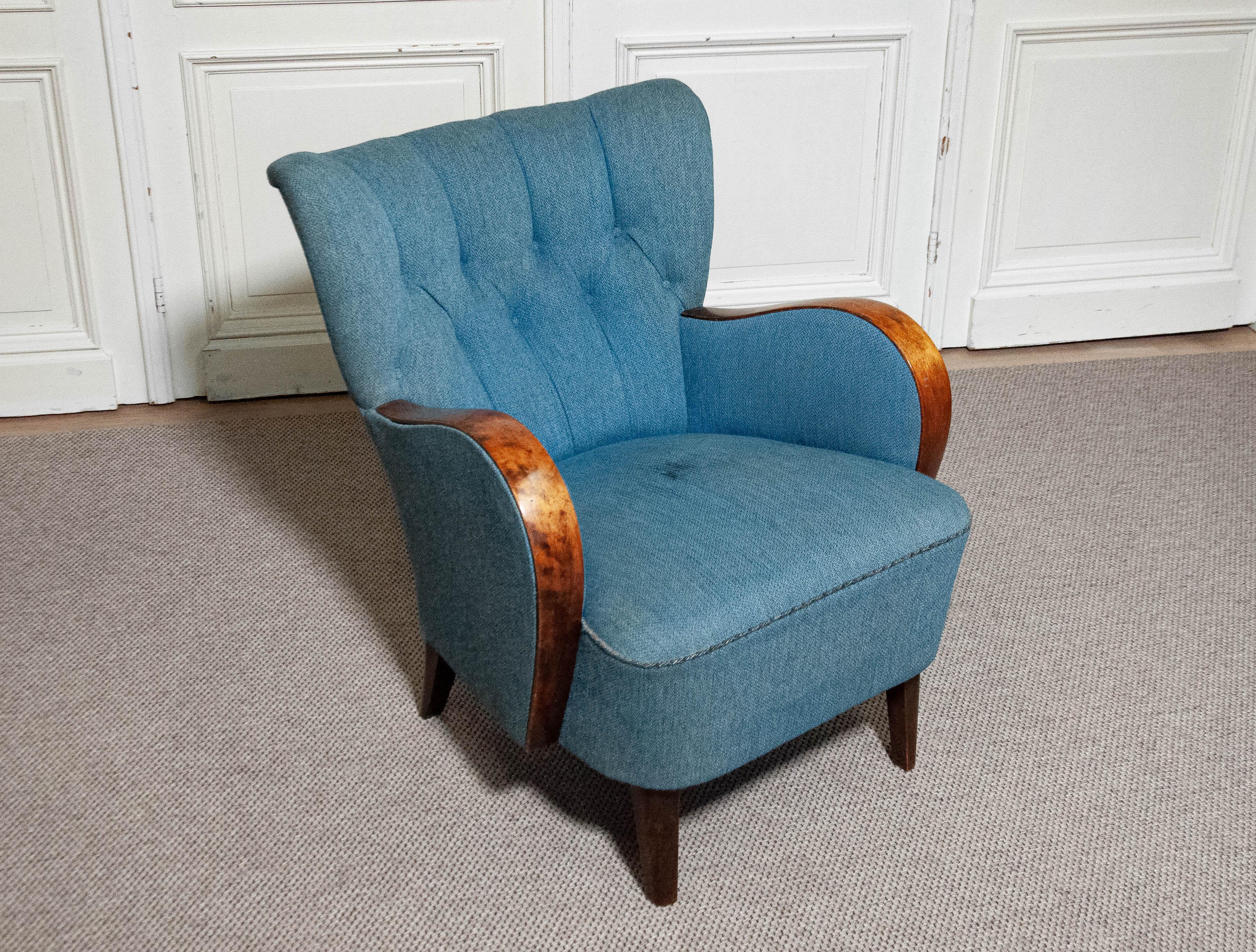 This is a Swedish Art Nouveau armchair from the 1940s, featuring a padded backrest and curved wooden armrests, adding an elegant and timeless design. The chair offer exceptional comfort and has been dry-cleaned, ensuring it is fresh and odor-free.