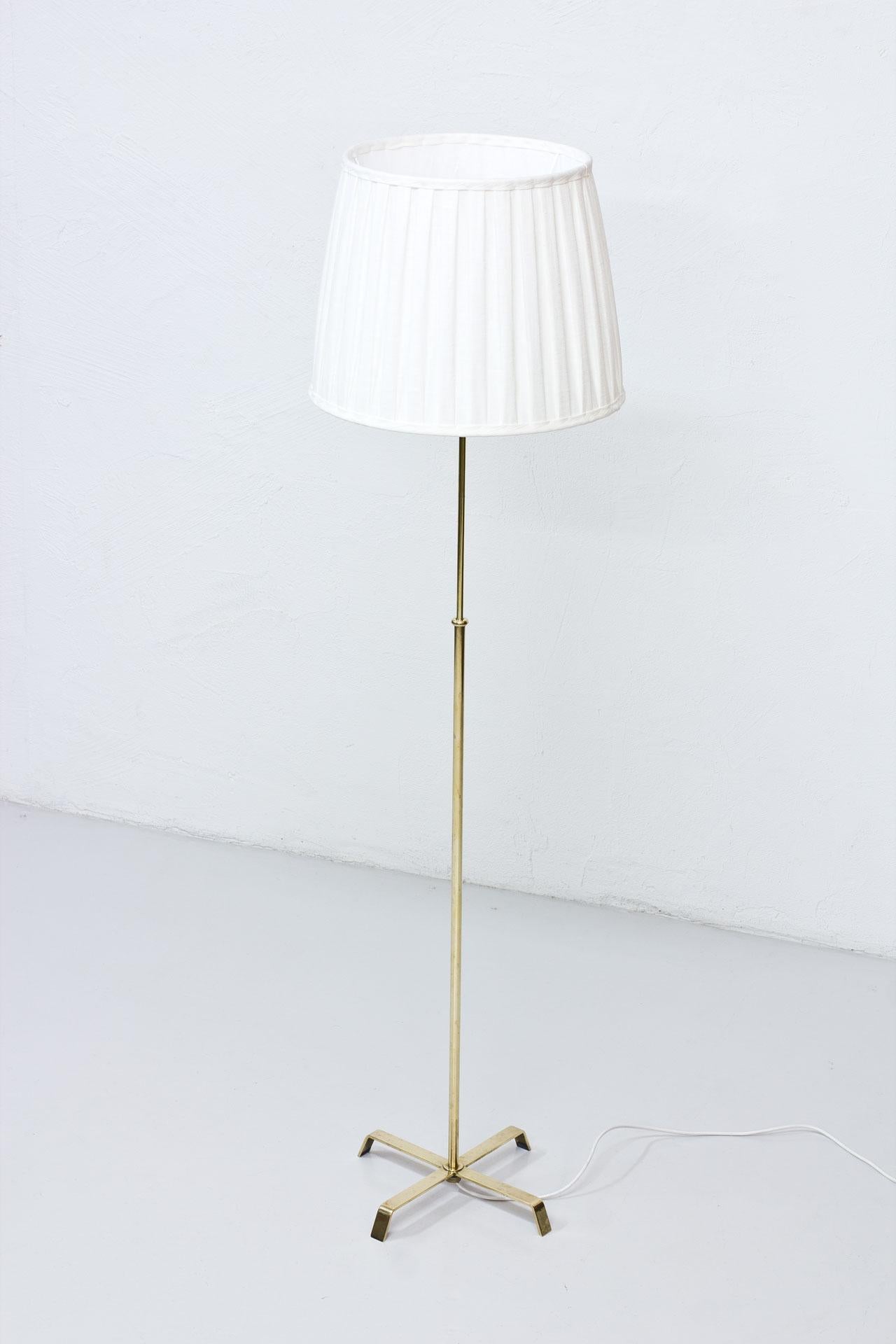Floor lamp manufactured in Sweden by Böhlmarks lampfabrik during the 1940s. Made from brass with hand pleated lamp shade in linen fabric. Adjustable height of the stem. Engraved on the base.