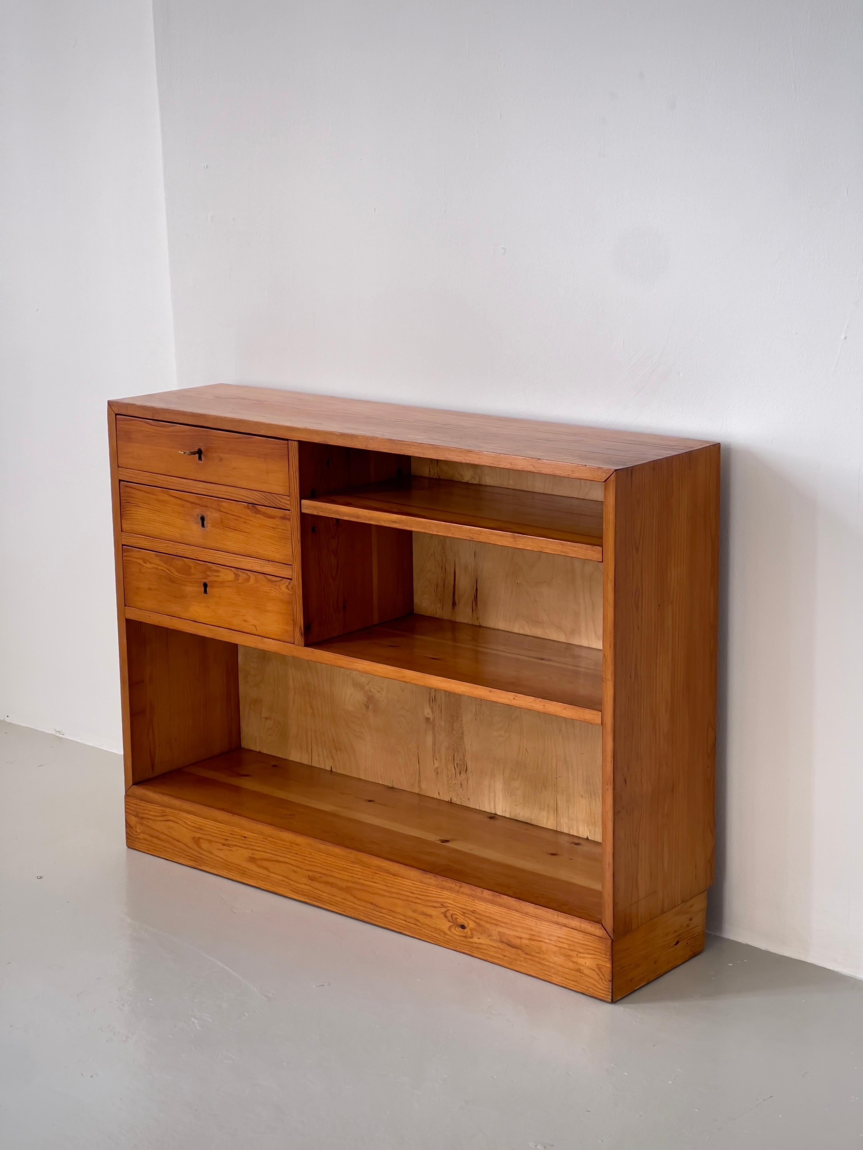 This robust 1940s Swedish console or chest of drawers, attributed to renowned designer Axel Einar Hjorth, exemplifies the refined simplicity and tactile richness of Scandinavian modernist craft. Constructed in solid pine with a deep, naturally aged