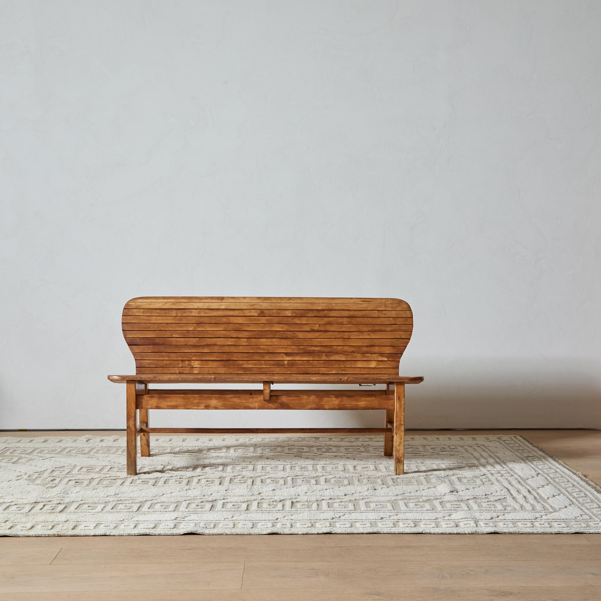 The seat and back of this Scandinavian Modern bench comprise a stylish wave of conjoined slats. Set on sturdy tapered legs, this is a design with a compelling presence.