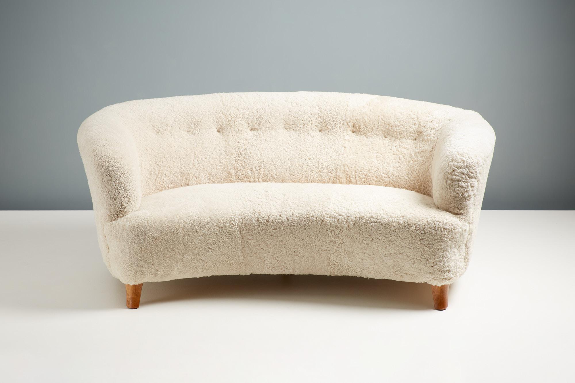 Magnifique canapé courbé conçu et produit au début des années 1940. Les pieds sont en bois d'orme teinté restauré et le canapé a été retapissé en peau de mouton Skandilock « Moonlight ».