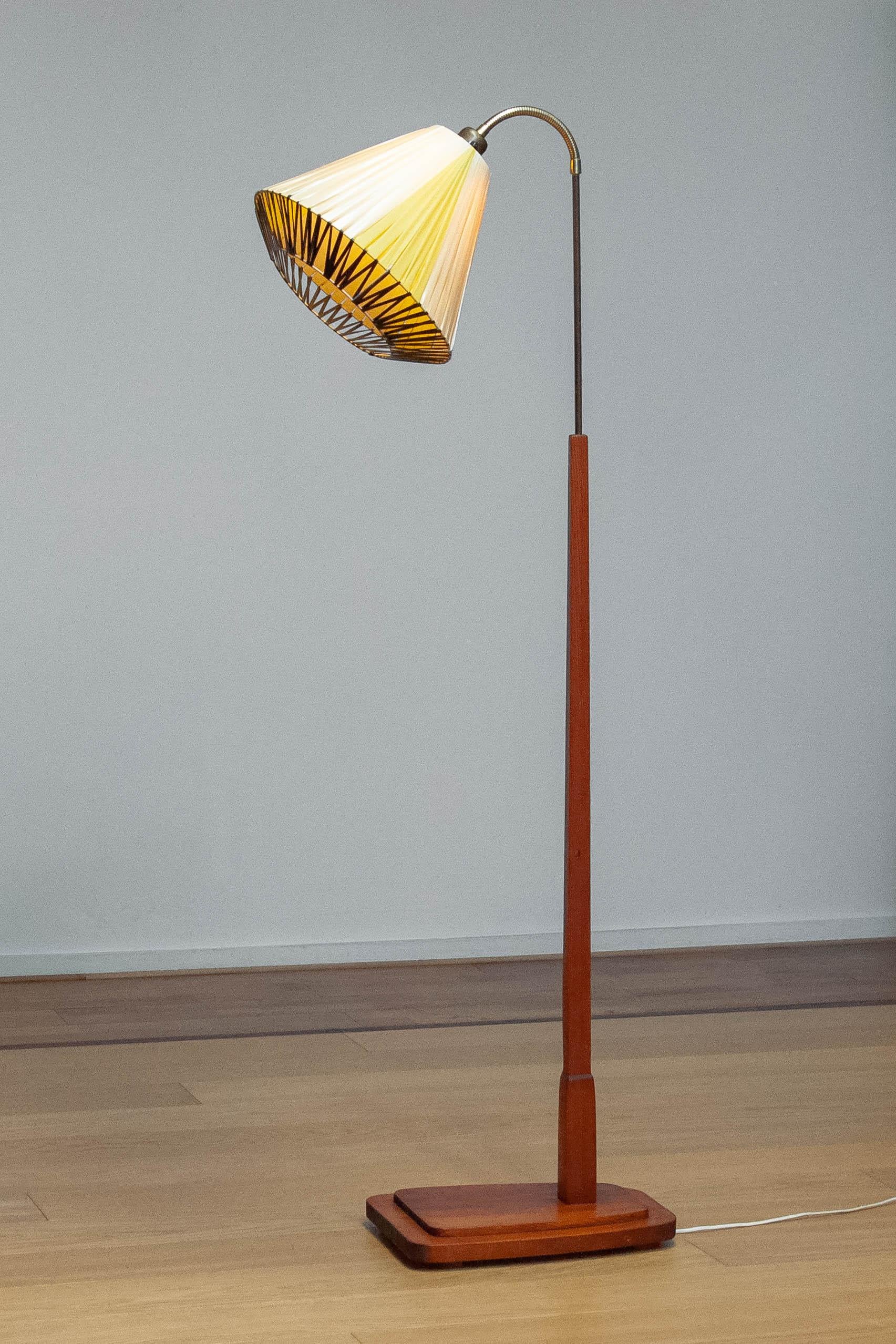 Beautiful and decorative Swedish floor lamp with square pine base and brass rod on top a flexible neck connecting the screw fitting, size E28.
The lampshade is made of steel wire with polyester ribbon, in two tones beige and black,  wrapped around
